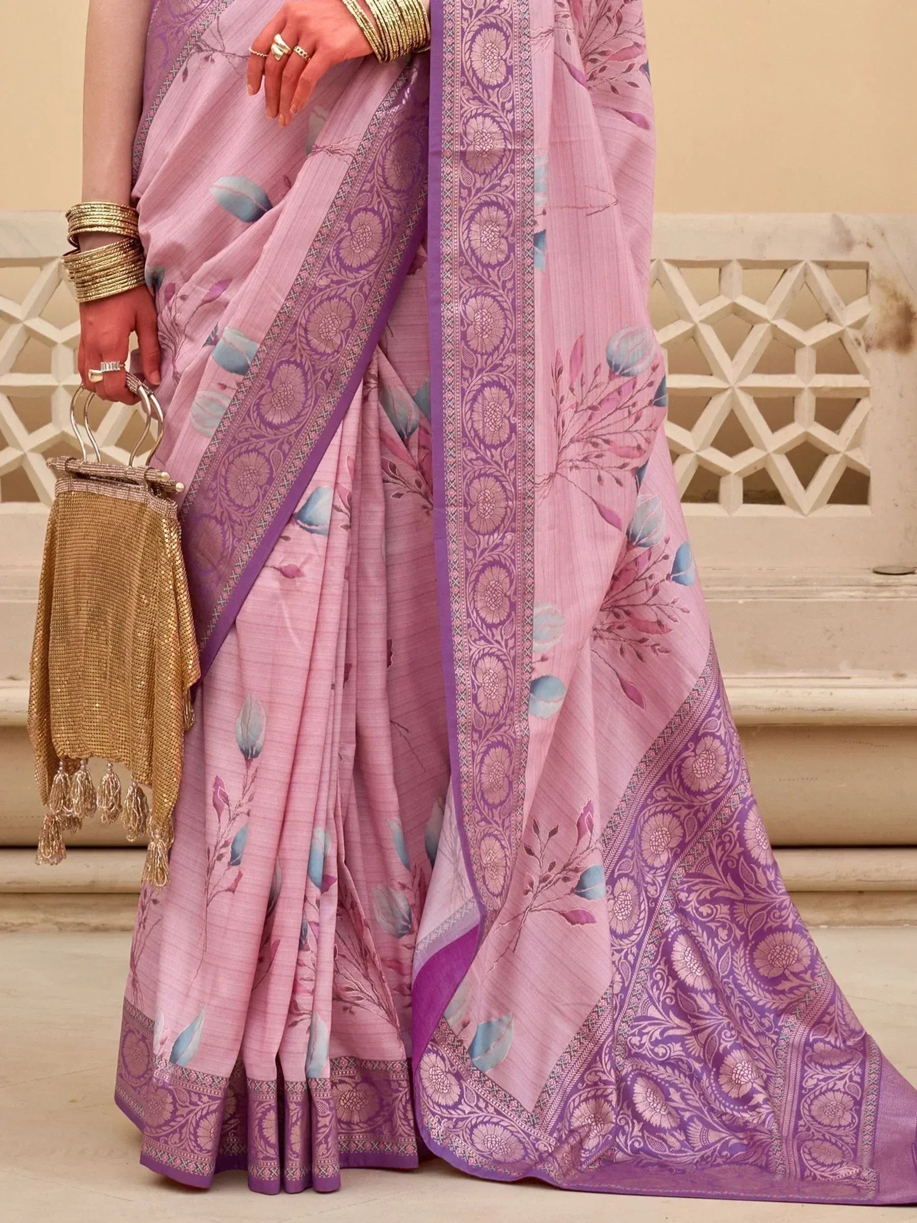 Pink floral saree with purple border, gold bangles, and ethnic handbag for Indian ethnic wear