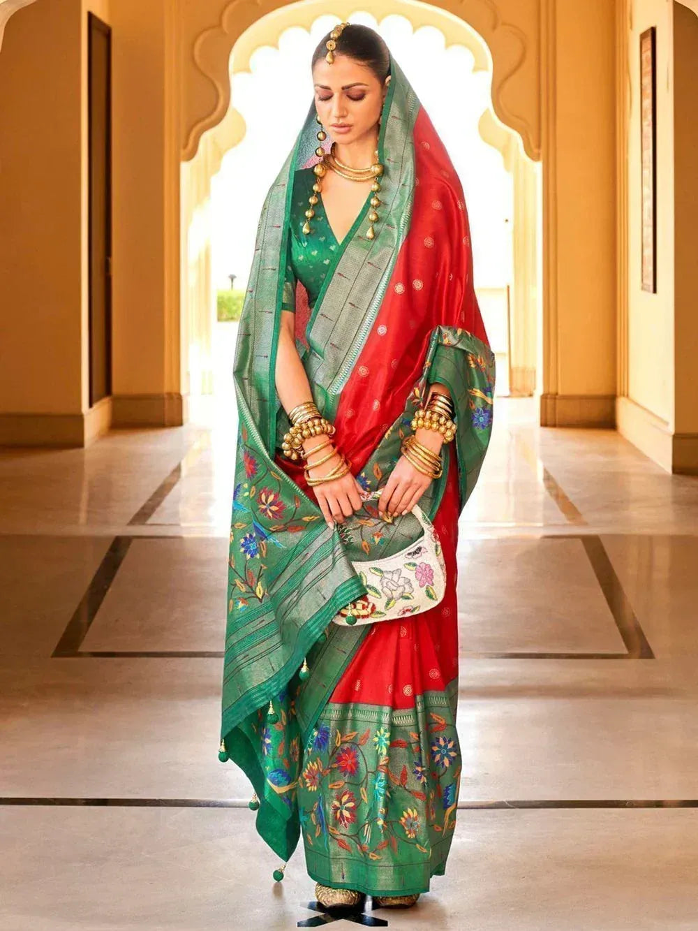 Woman in red and green embroidered saree with gold jewelry, traditional Indian ethnic wear