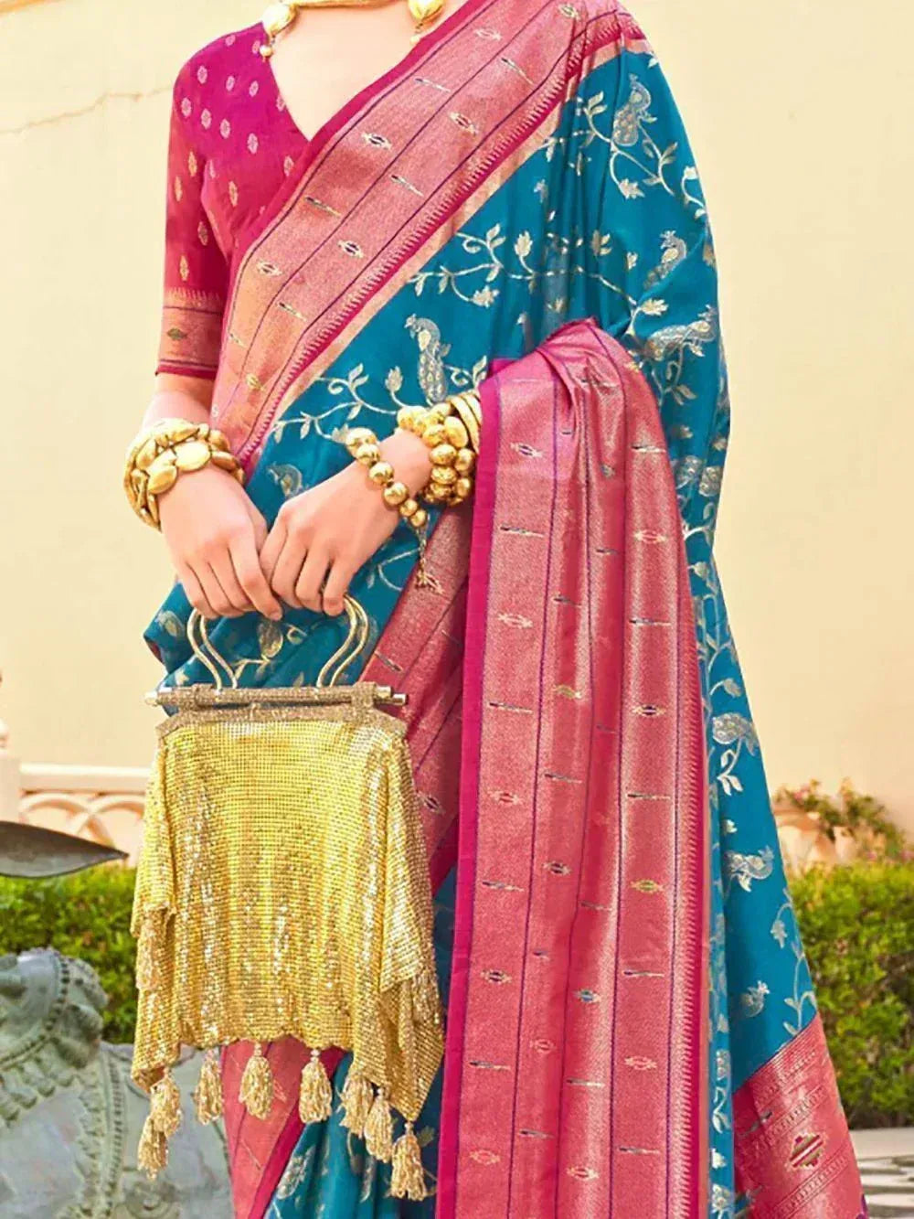 Teal and pink embroidered saree with gold jewelry and sequin handbag, perfect for Indian ethnic occasions
