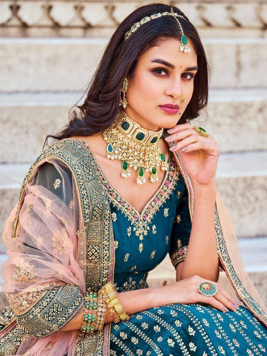 Elegant teal embroidered lehenga choli with gold jewelry and sheer dupatta, perfect for Indian ethnic occasions.