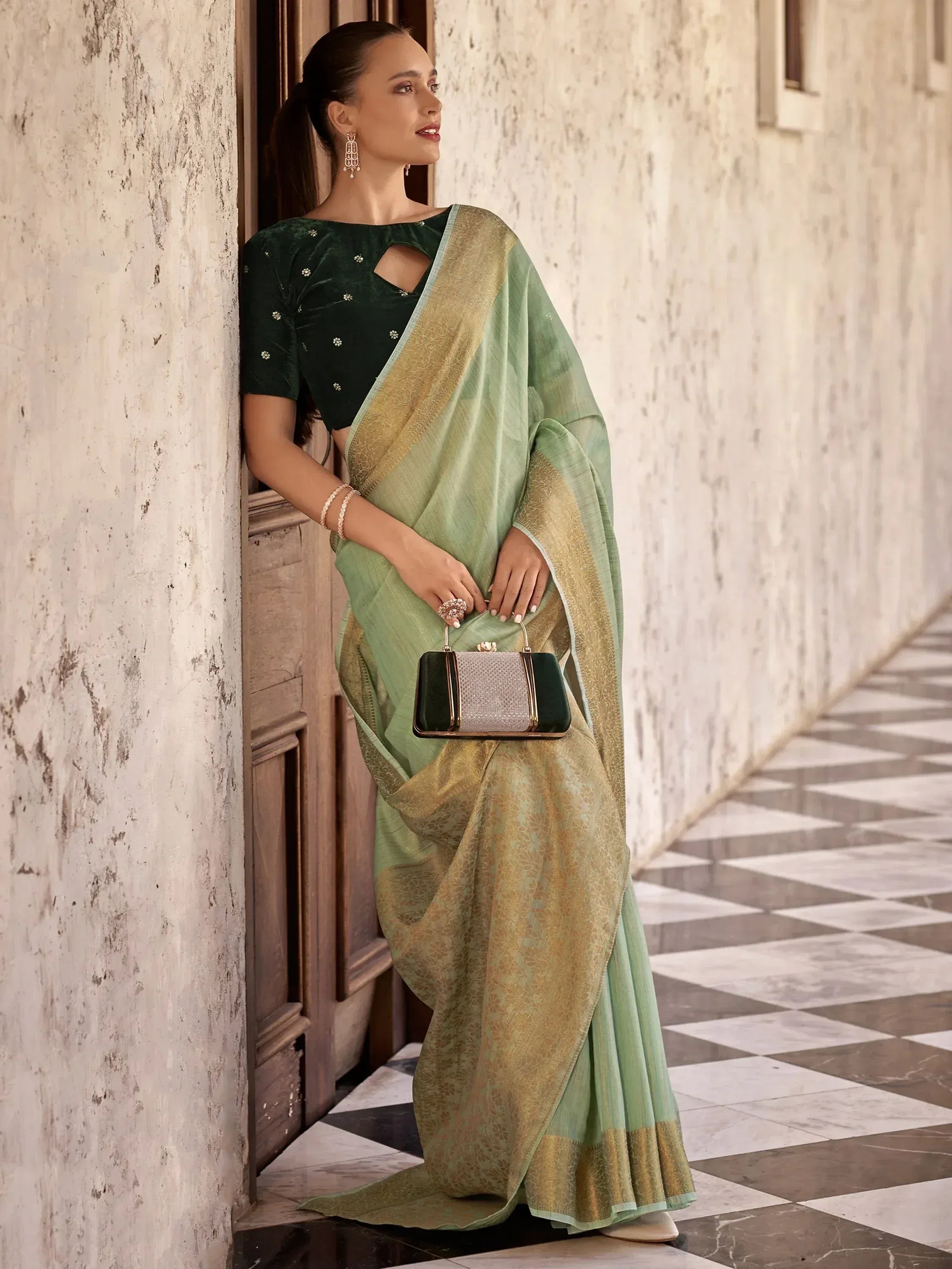 Woman in elegant green saree with gold border and velvet blouse, styled for Indian ethnic wear occasions