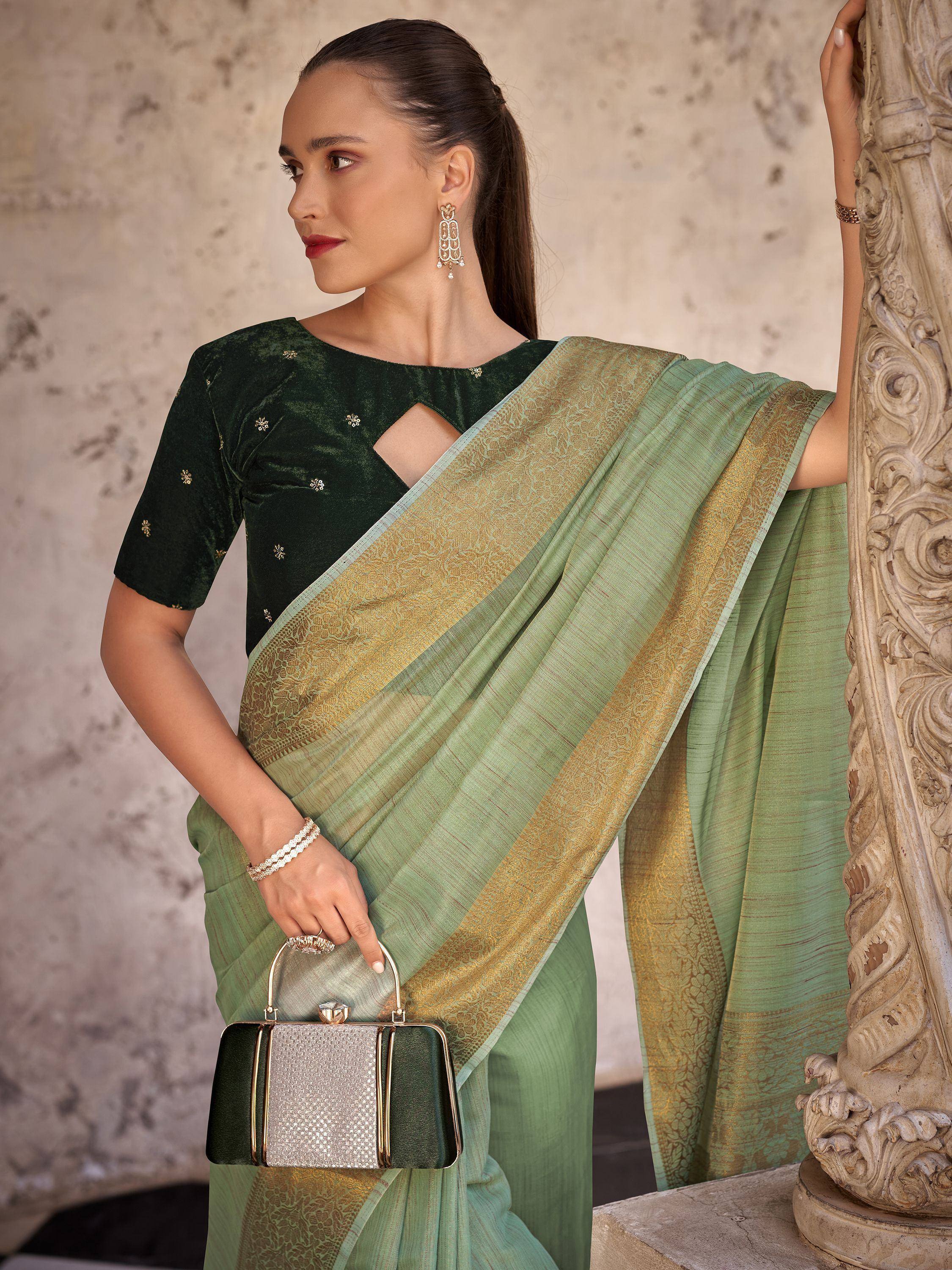 Elegant green saree with gold border, paired with embroidered velvet blouse and clutch, perfect for Indian ethnic occasions.