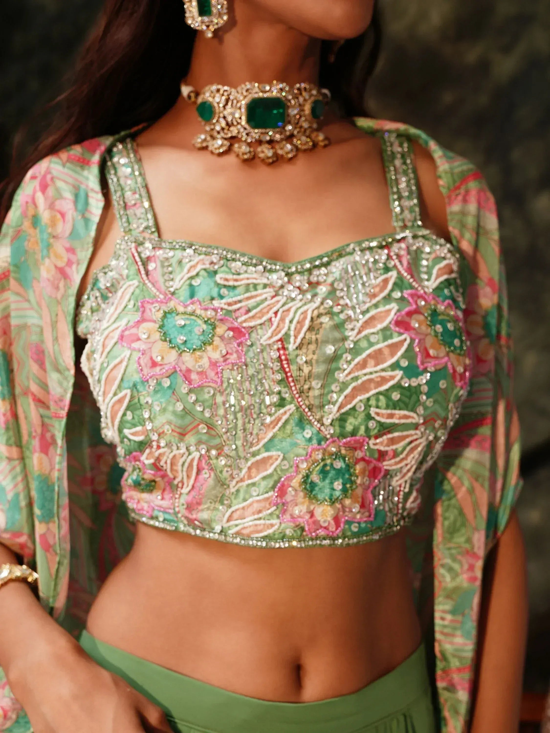 Green floral embroidered lehenga choli with pearl and stone work, paired with emerald jewelry