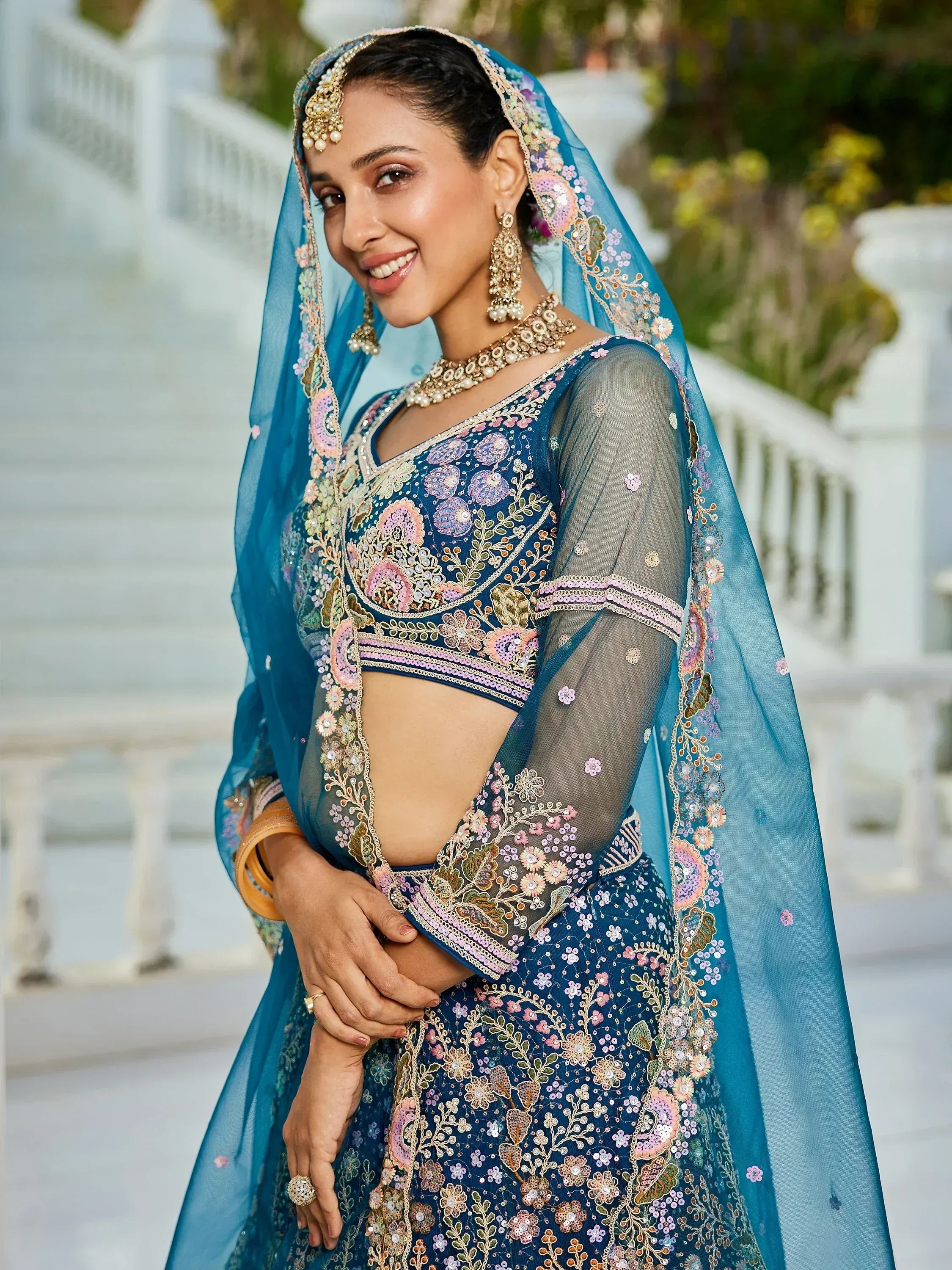 Blue embroidered lehenga choli with floral motifs and sheer dupatta, perfect for Indian weddings or festive occasions.