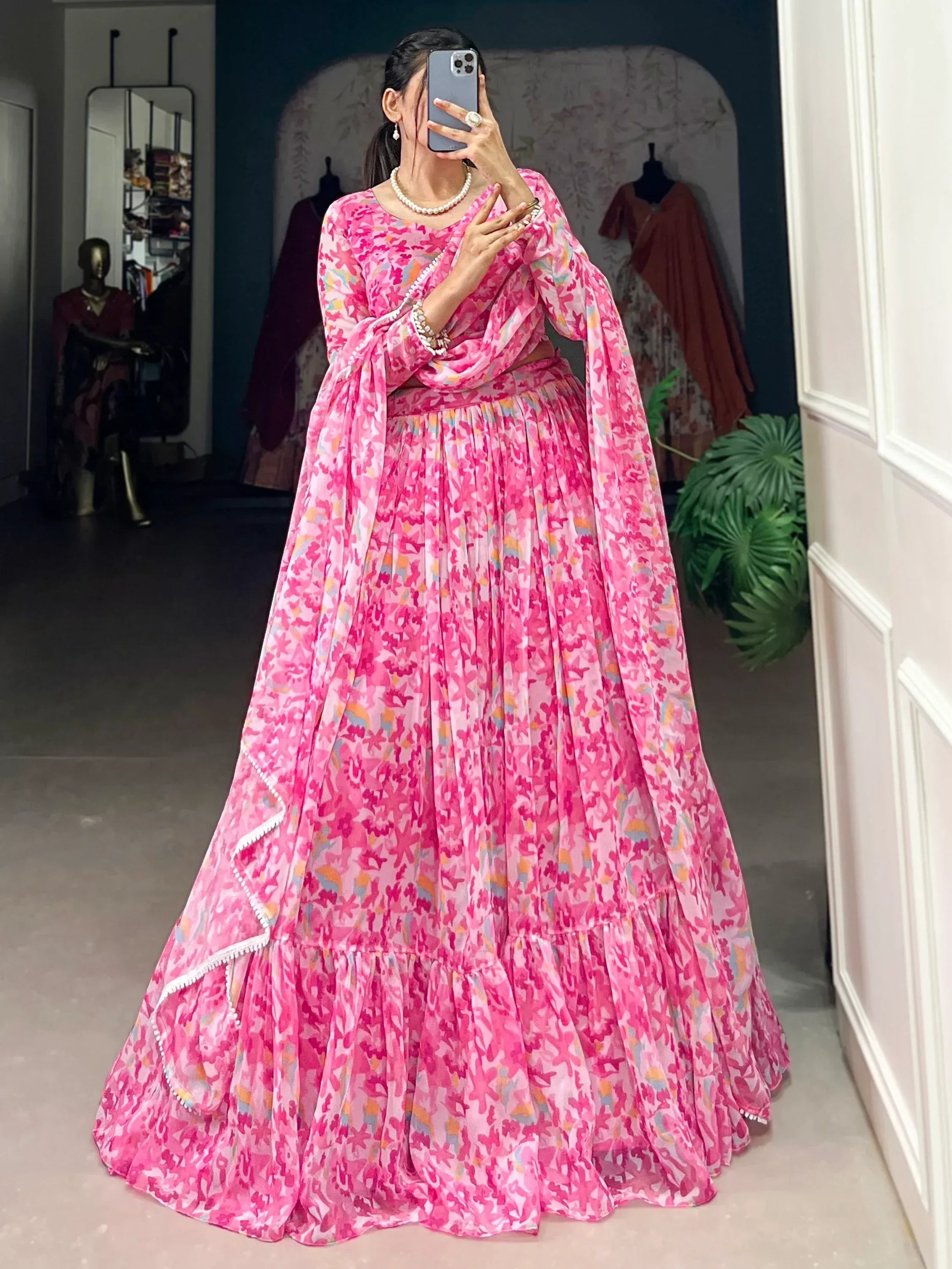 Pink floral print lehenga choli with ruffled skirt and pearl jewelry, perfect for Indian ethnic occasions.