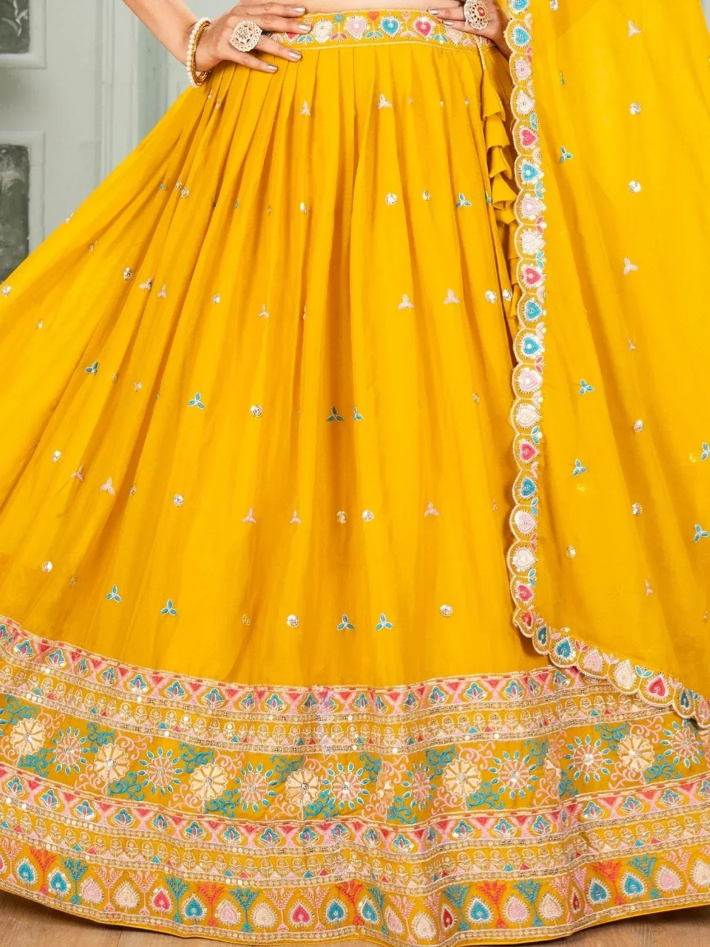 Vibrant yellow lehenga choli with colorful floral embroidery and mirror work, perfect for Indian ethnic occasions.