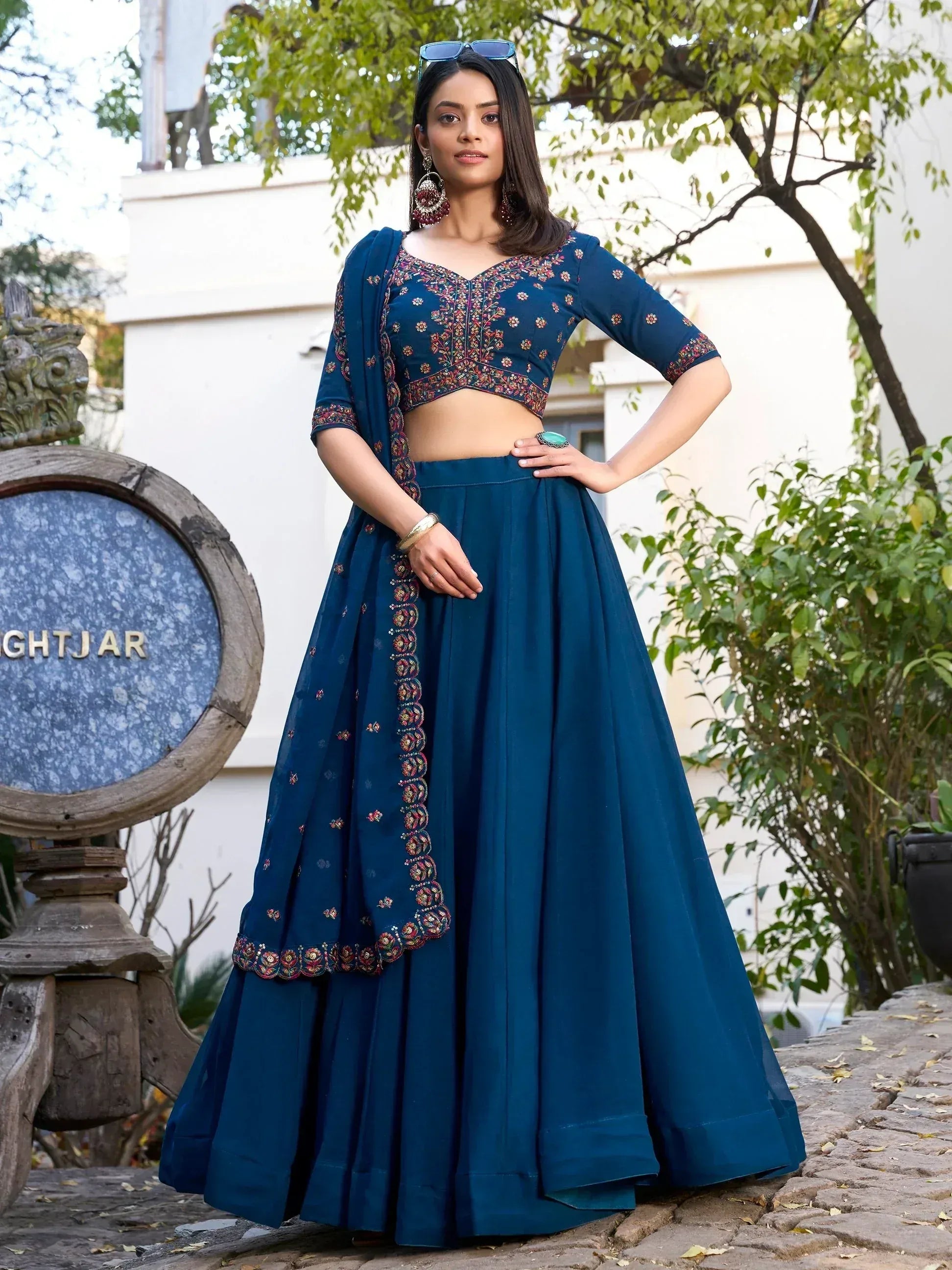 Woman in navy blue embroidered lehenga choli with floral detailing, perfect for Indian ethnic wear occasions