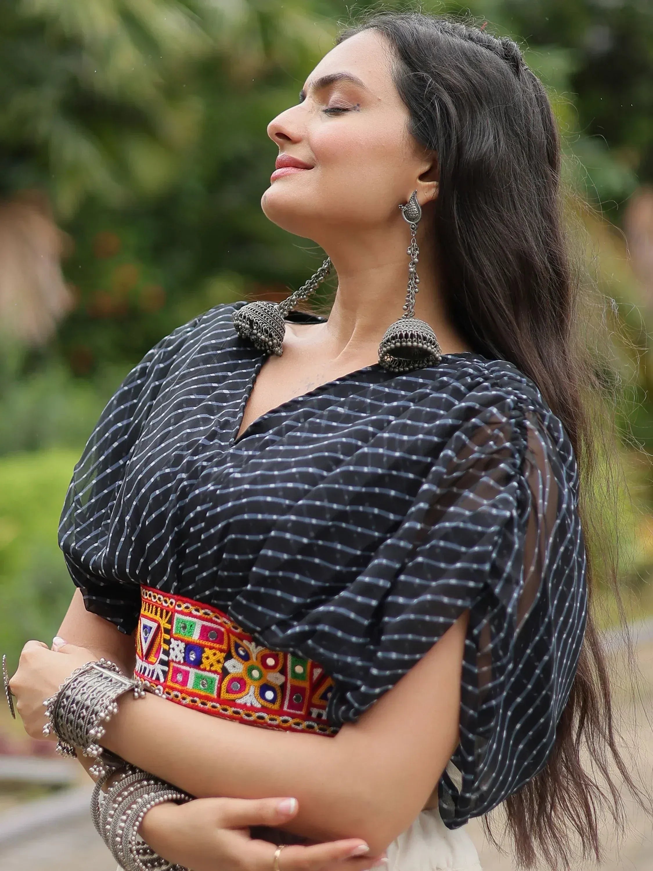 Woman in black striped ethnic top with colorful embroidered belt and silver jewelry