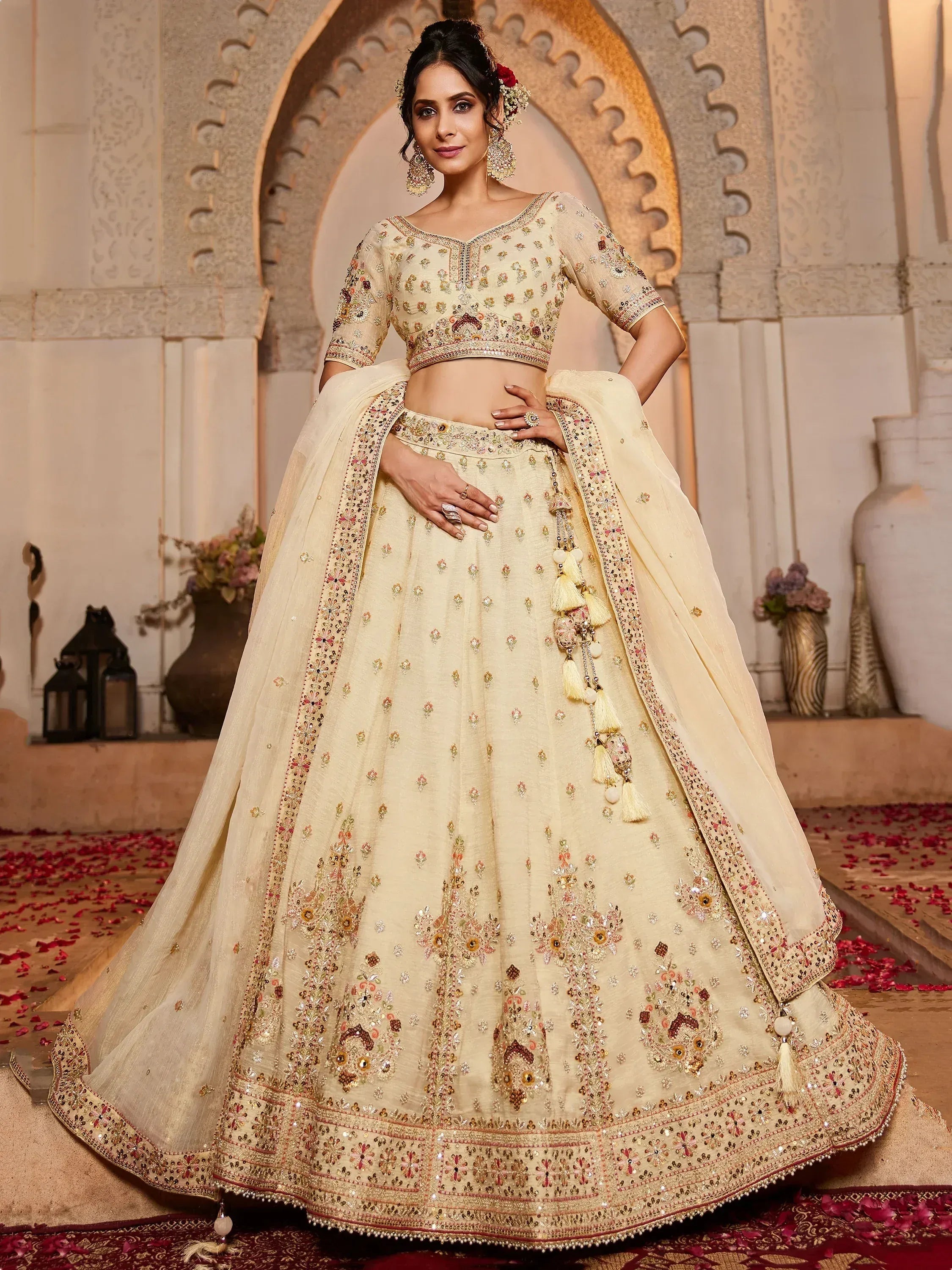 Elegant cream lehenga choli with intricate floral embroidery and tassels, perfect for Indian weddings and festive occasions.
