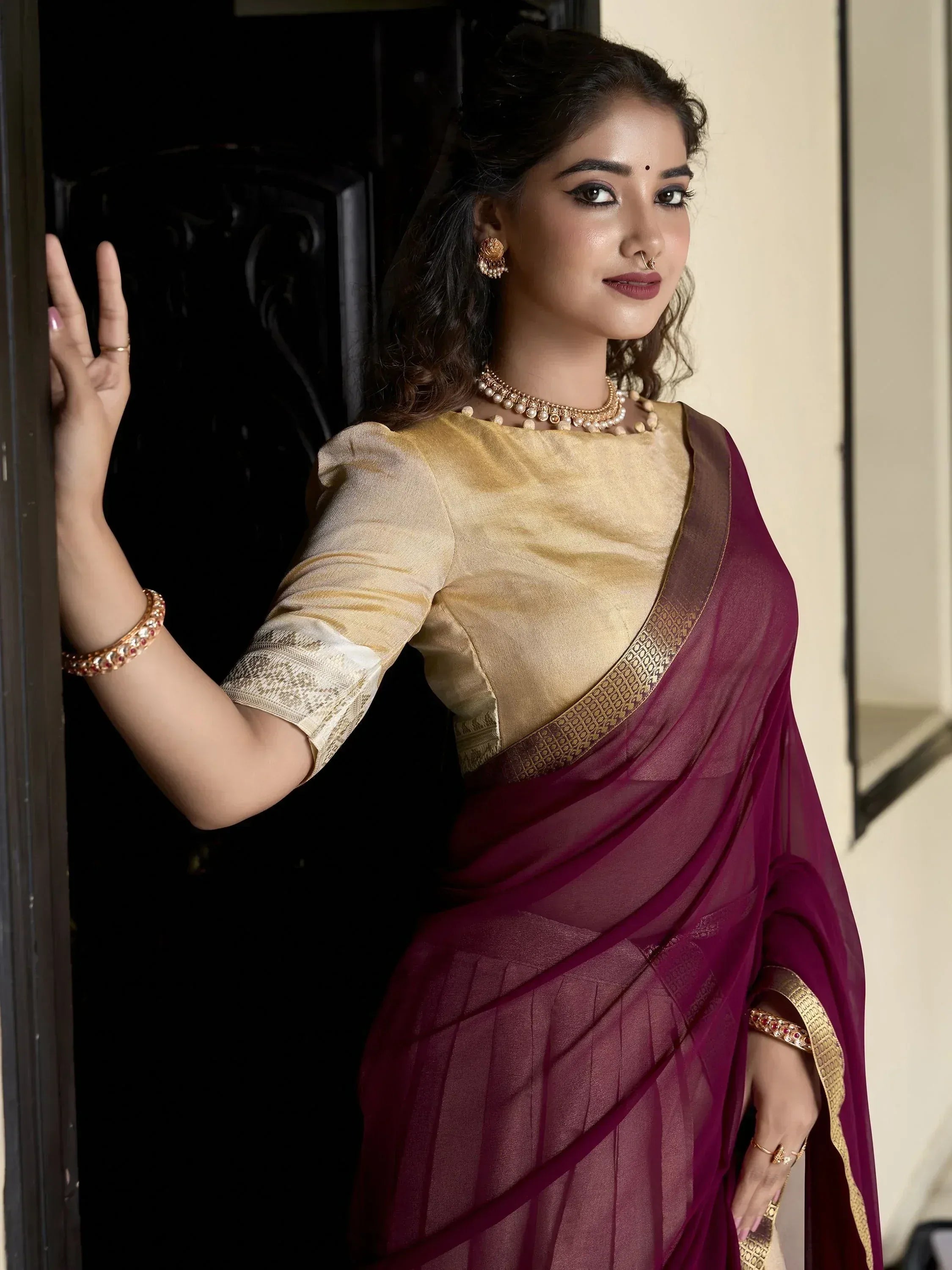 Woman in maroon saree with gold blouse, traditional Indian ethnic wear, styled with jewelry
