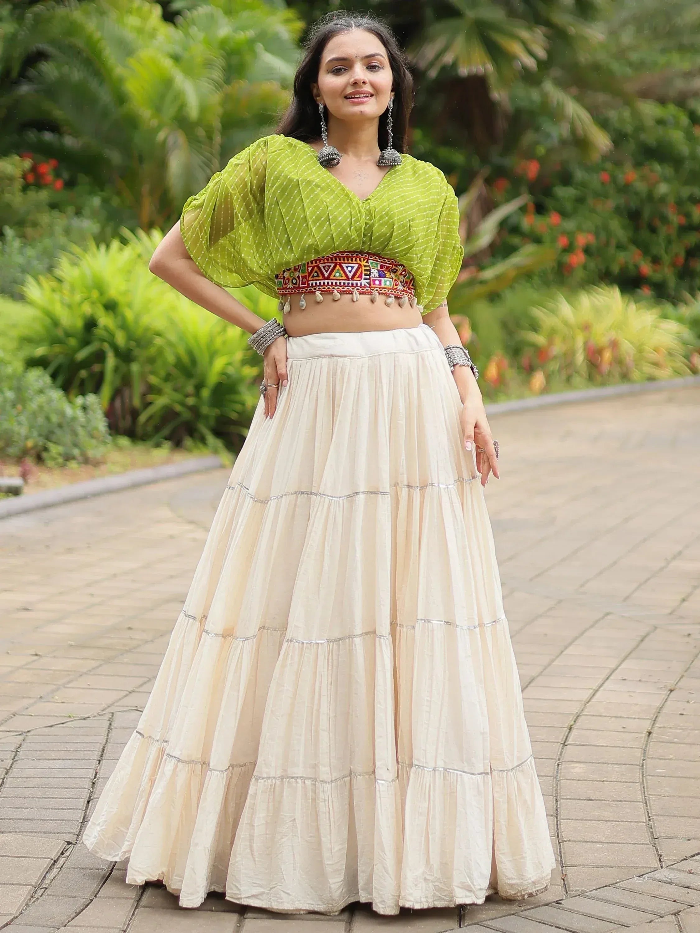 Woman in green printed crop top with embroidered belt and cream tiered skirt, ethnic wear outfit