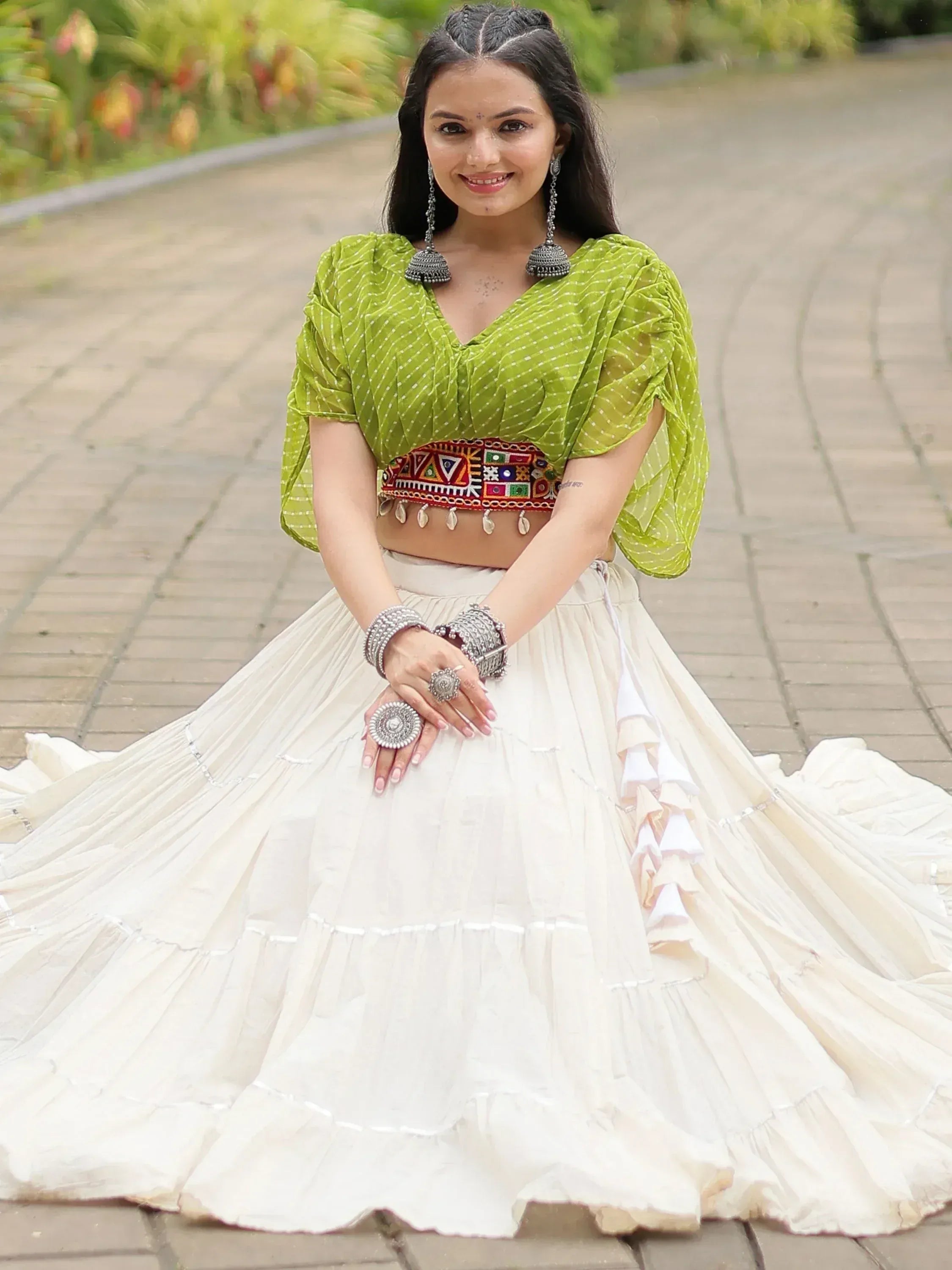 Woman in green polka dot crop top with embroidered waistband and white flared lehenga skirt, styled with silver jewelry