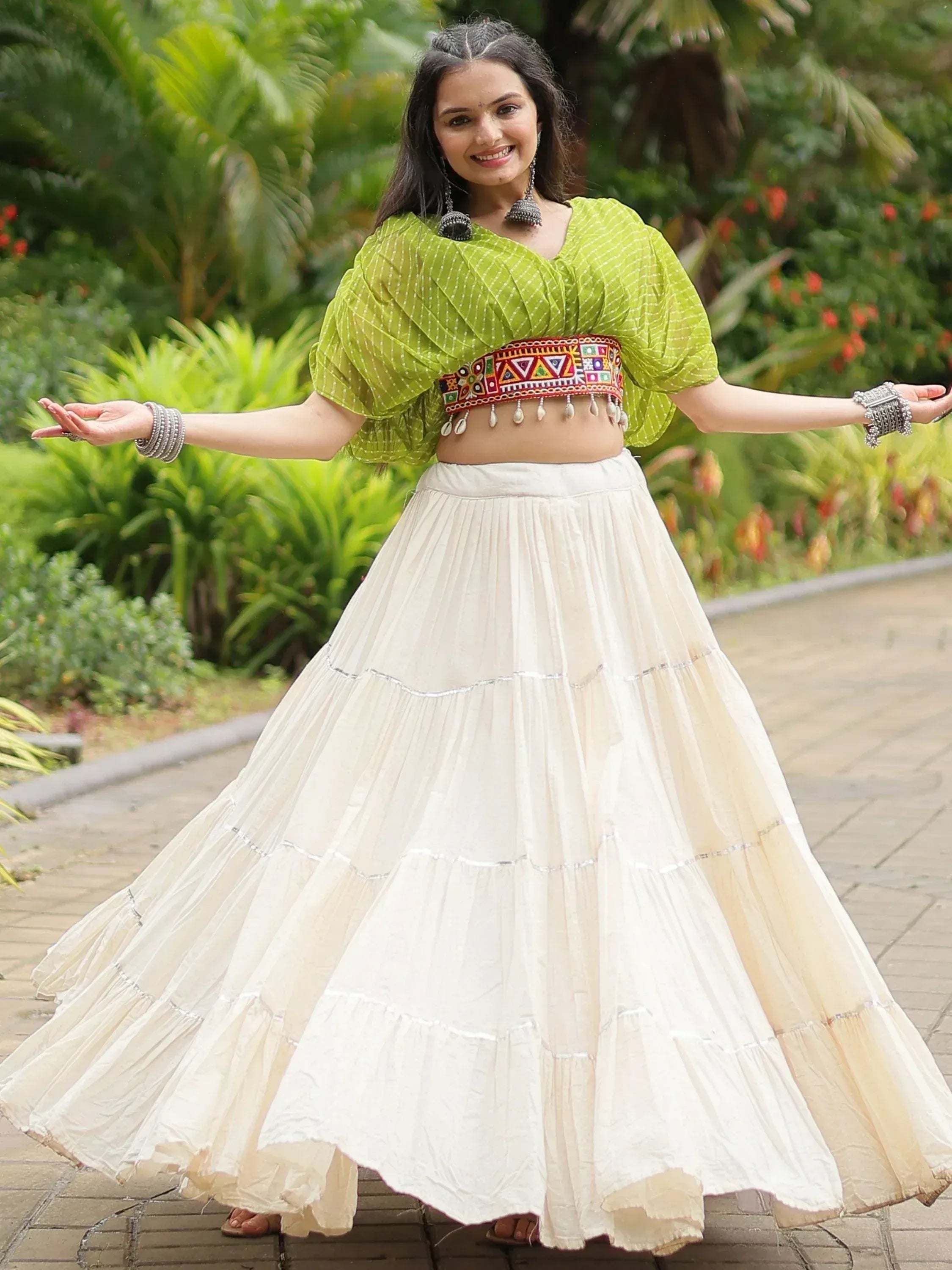 Woman in green printed crop top with embroidered belt and white tiered skirt, ethnic wear outfit