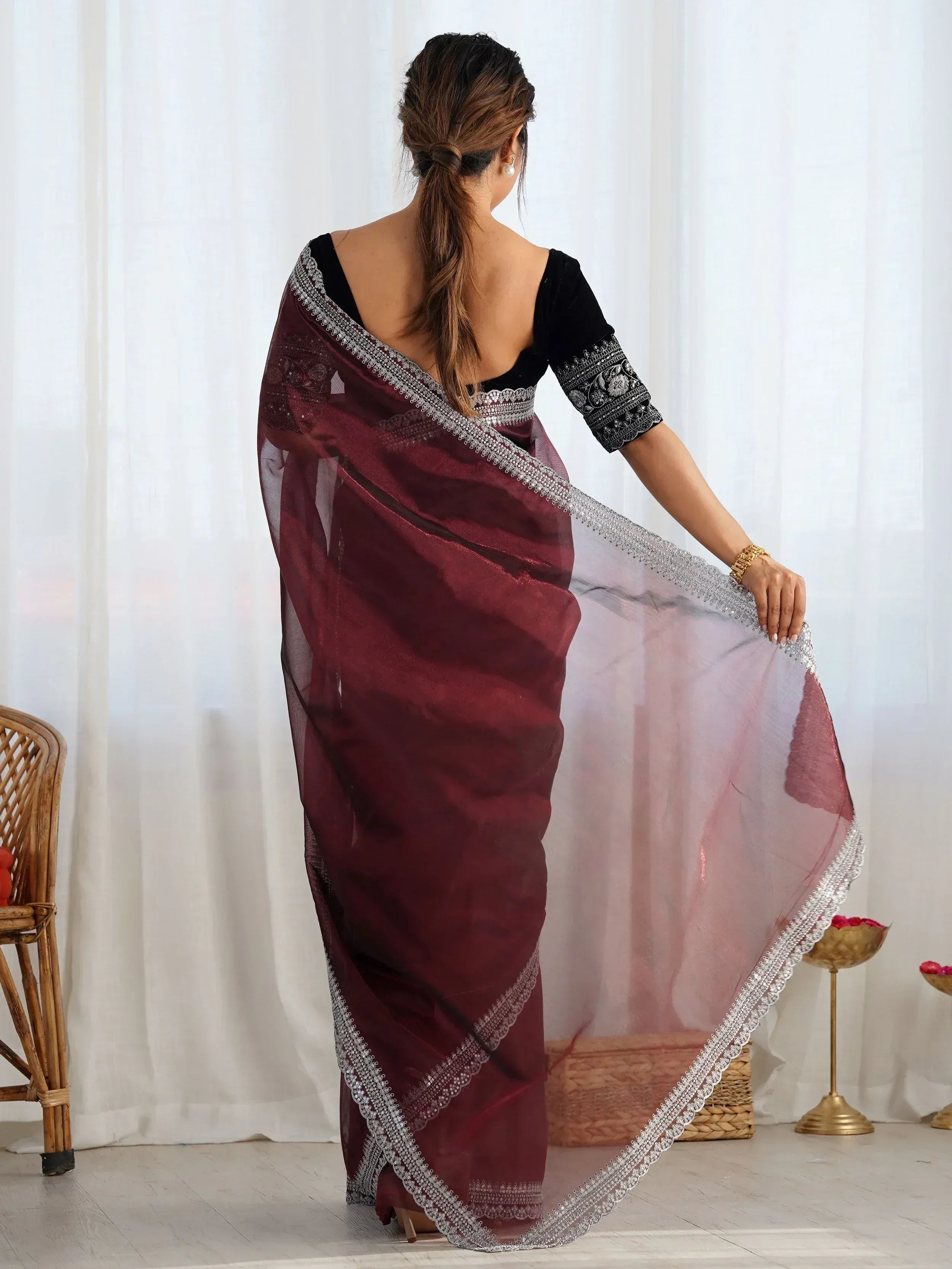 Woman in maroon saree with silver embroidery and black velvet blouse, showcasing ethnic Indian wear