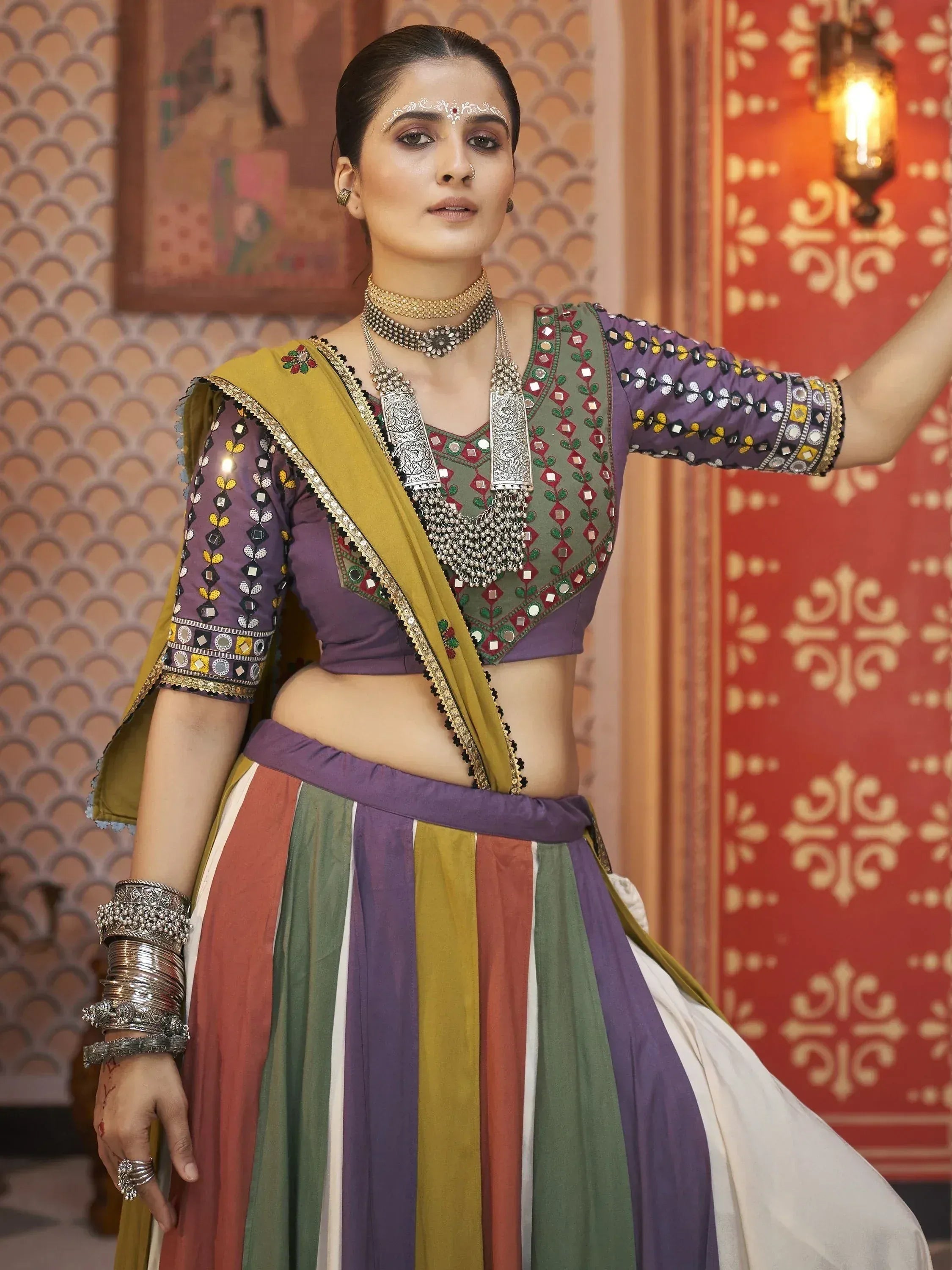 Woman in colorful Indian ethnic lehenga choli with mirror work, traditional jewelry, and dupatta