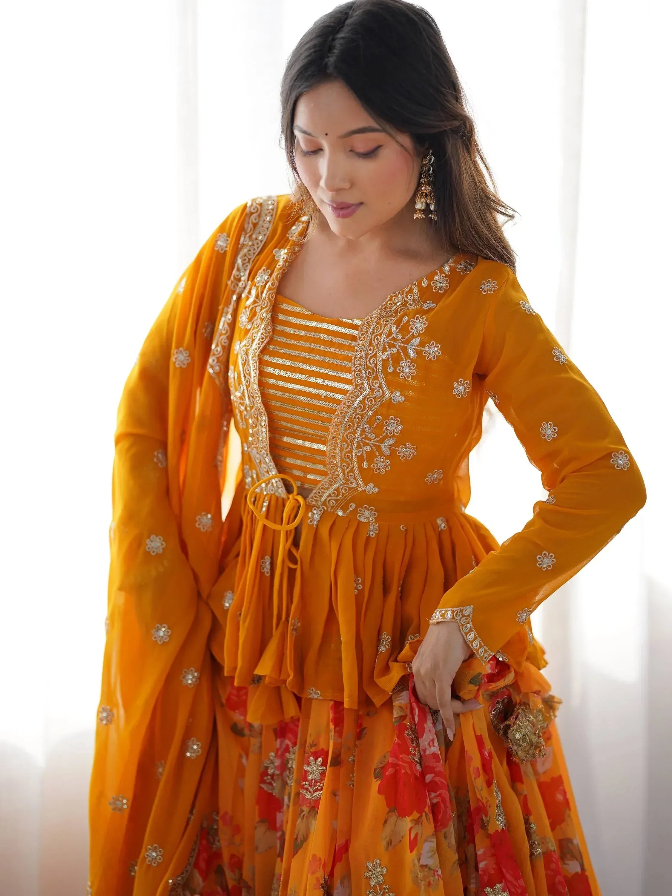 Woman in vibrant orange ethnic lehenga choli with floral embroidery and gold detailing, perfect for Indian celebrations.