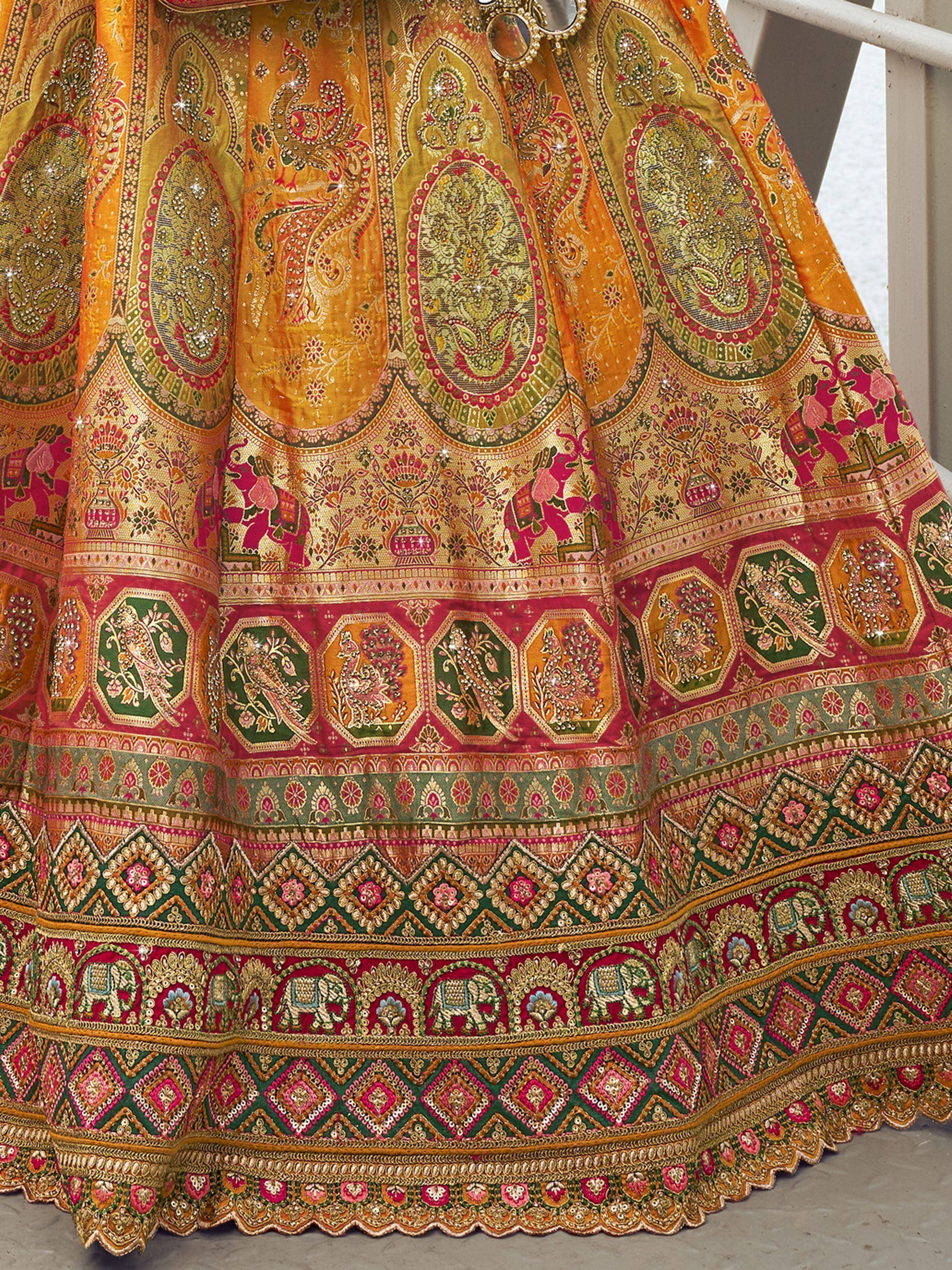 Luxury Indian lehenga with intricate paisley, elephant & peacock embroidery in gold, pink & green.