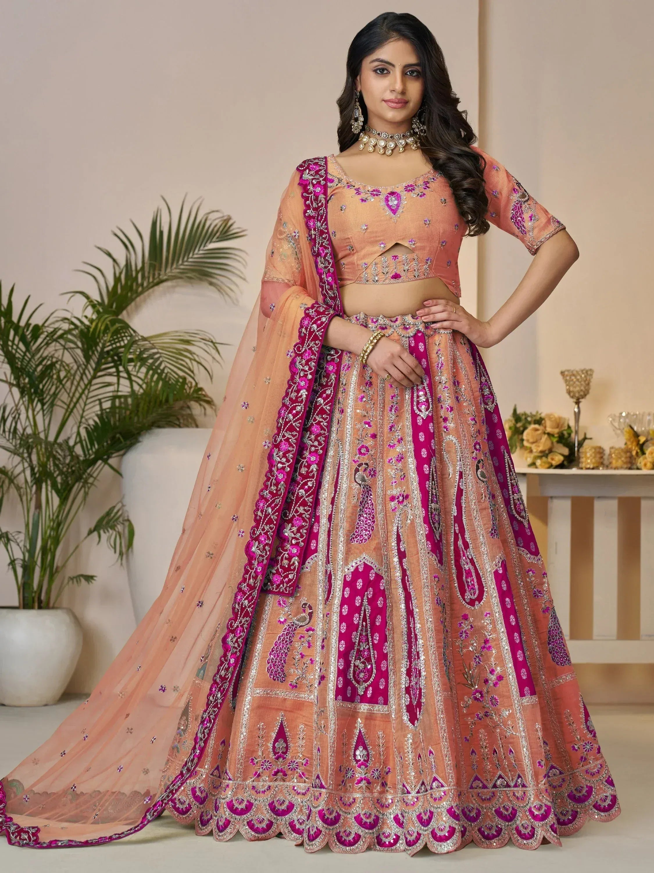 Elegant peach and magenta embroidered lehenga choli with peacock motifs, perfect for Indian weddings and festive occasions.