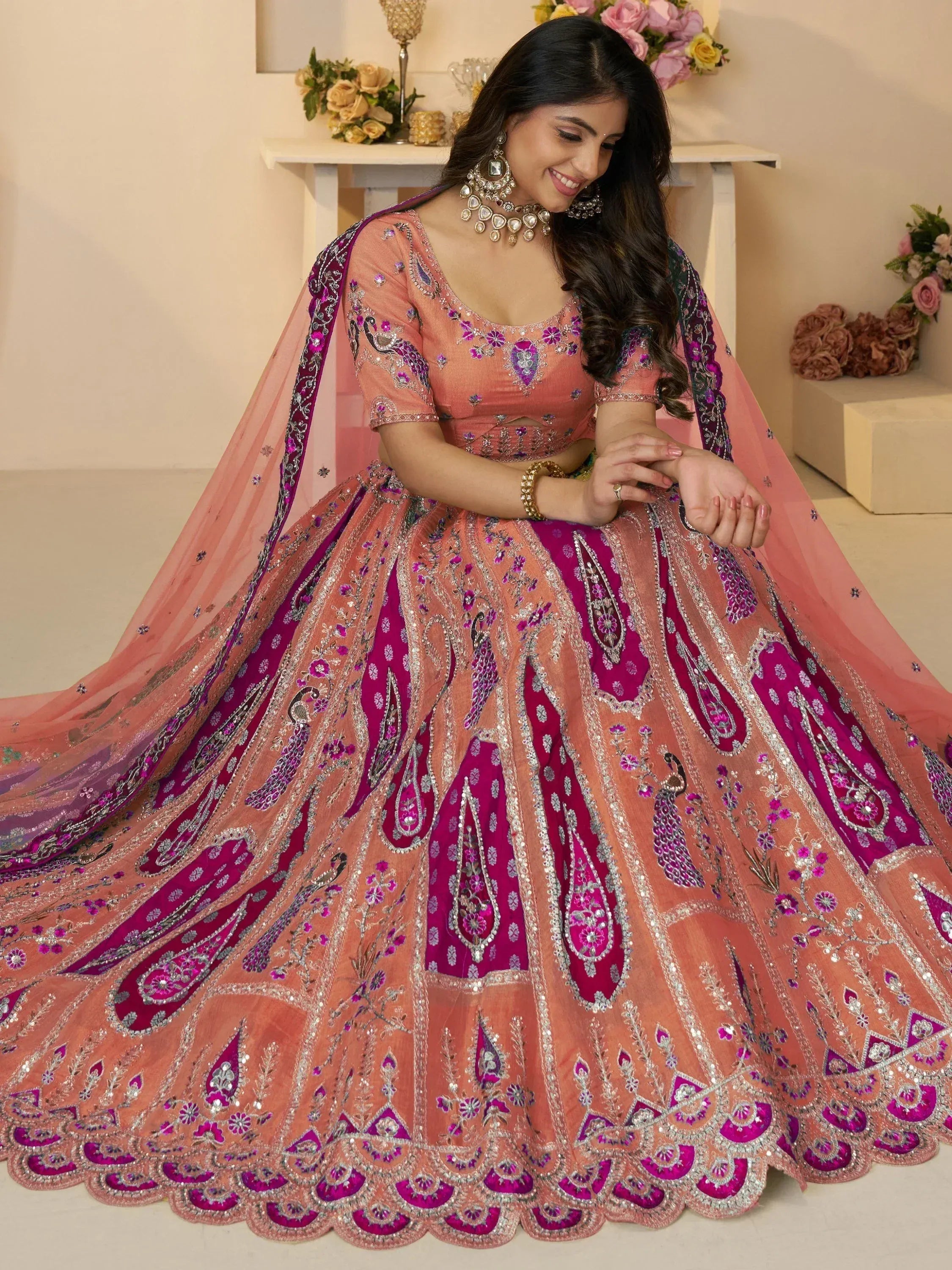 Elegant peach and magenta lehenga choli with intricate embroidery and peacock motifs, perfect for Indian weddings.