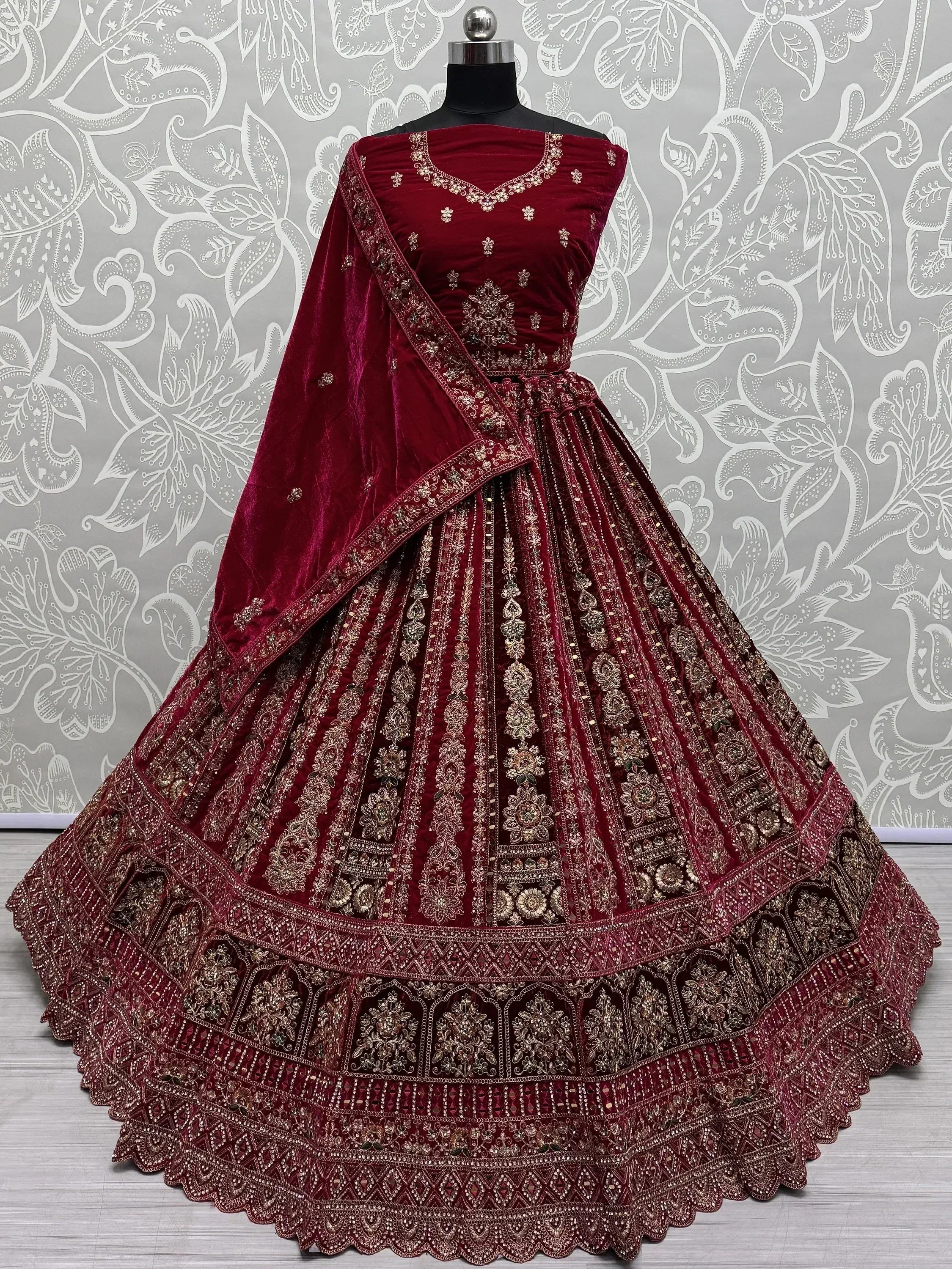 Burgundy velvet designer lehenga choli with gold embroidery and matching dupatta, perfect for Indian weddings and festive occasions.