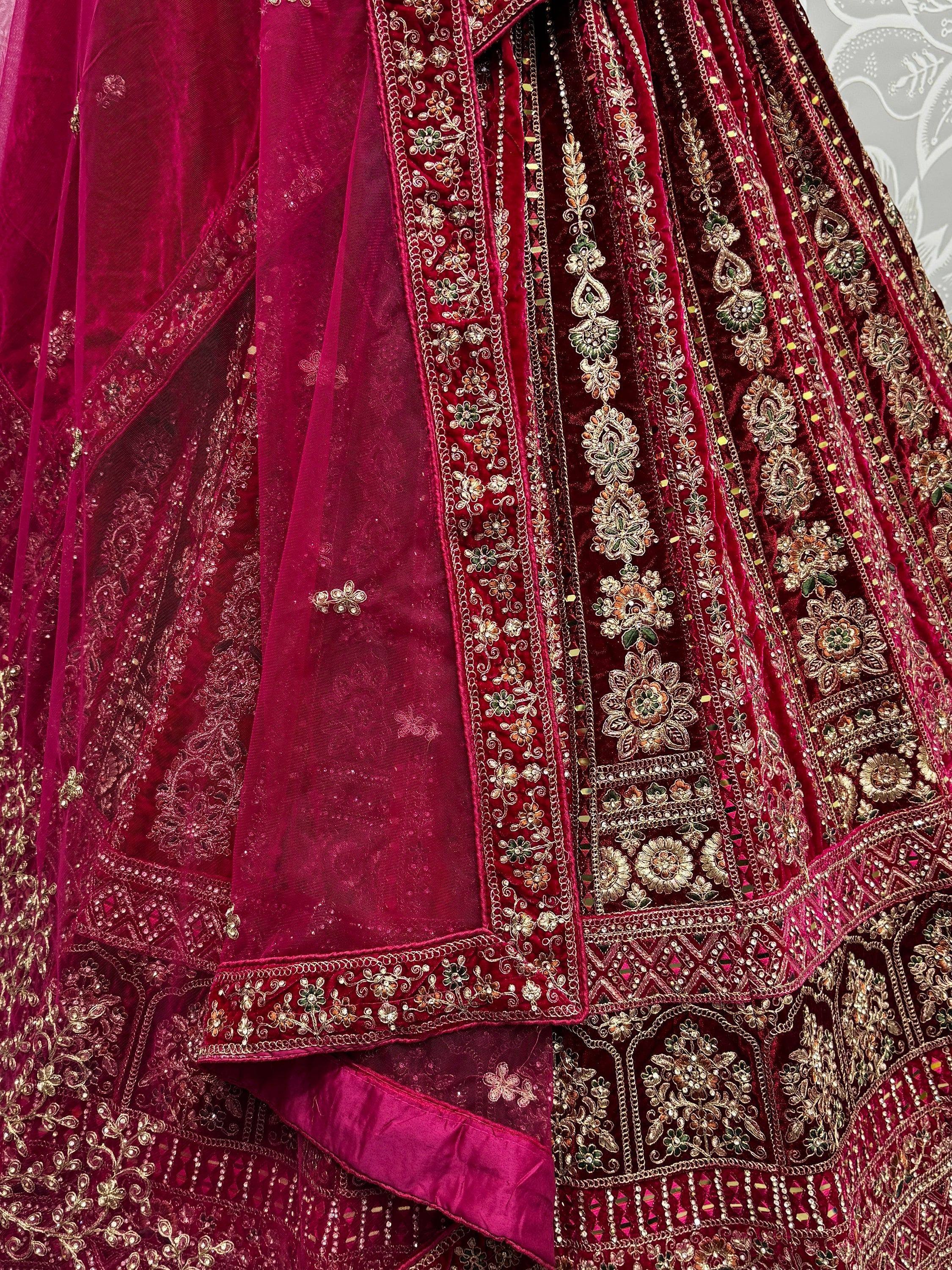 Luxury maroon velvet lehenga choli with intricate gold and green floral embroidery, perfect for Indian weddings.
