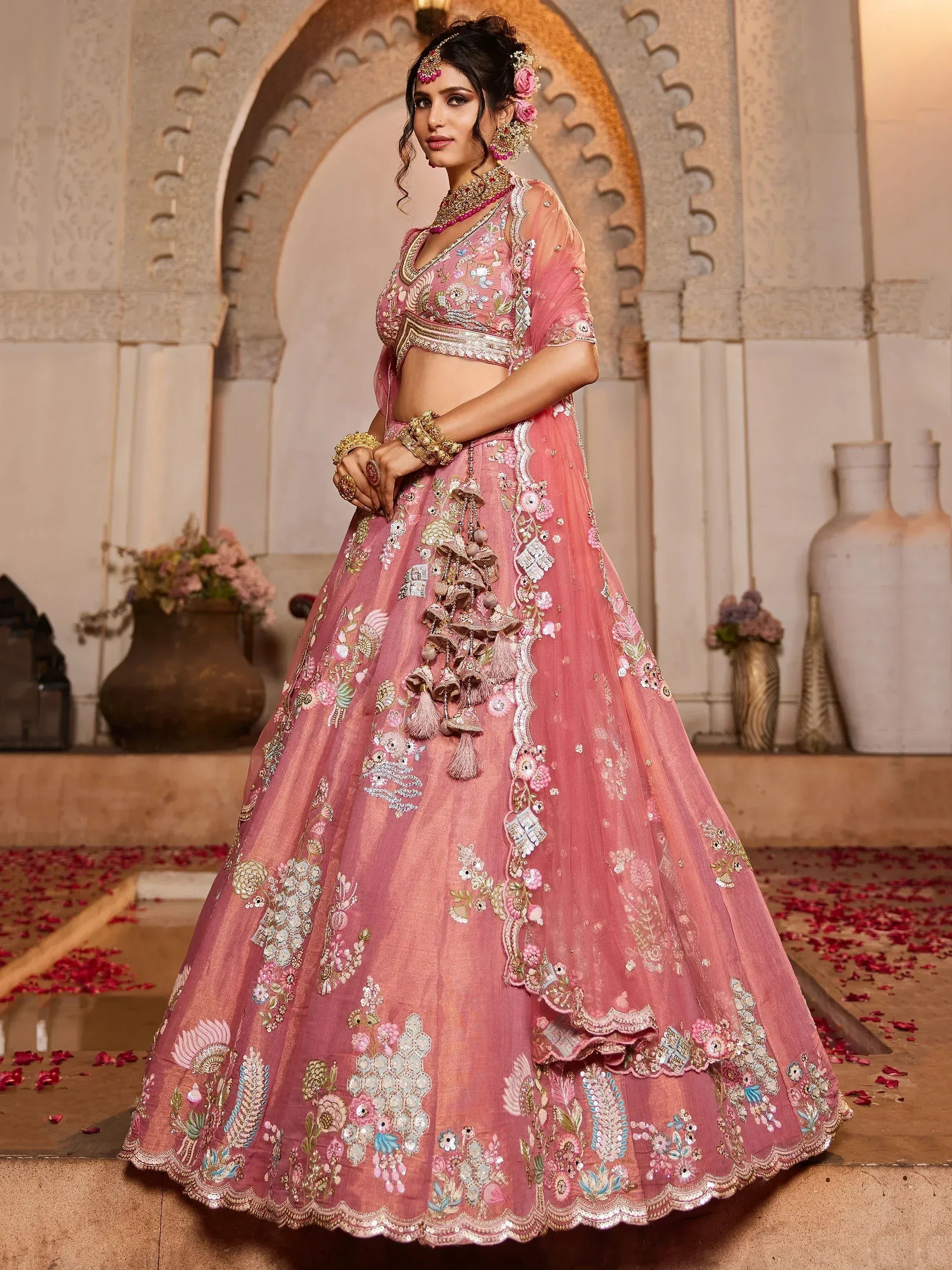 Pink embroidered lehenga choli with floral motifs and tassels, perfect for Indian weddings and festive occasions