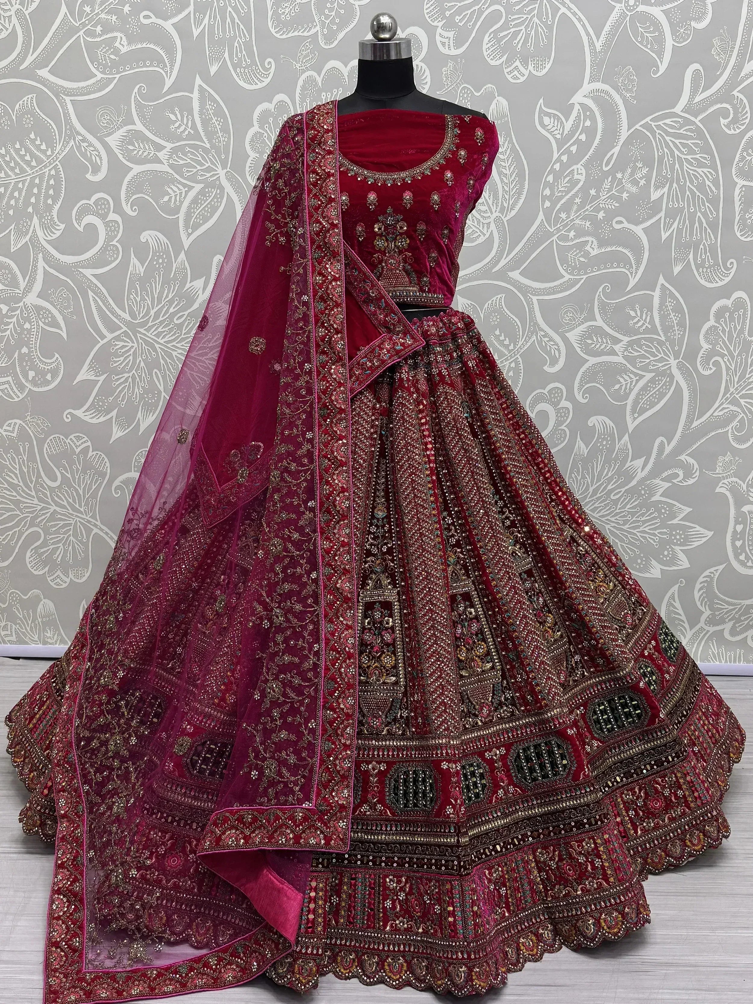 Burgundy velvet designer lehenga choli with heavy embroidery and net dupatta, perfect for weddings and festive occasions.