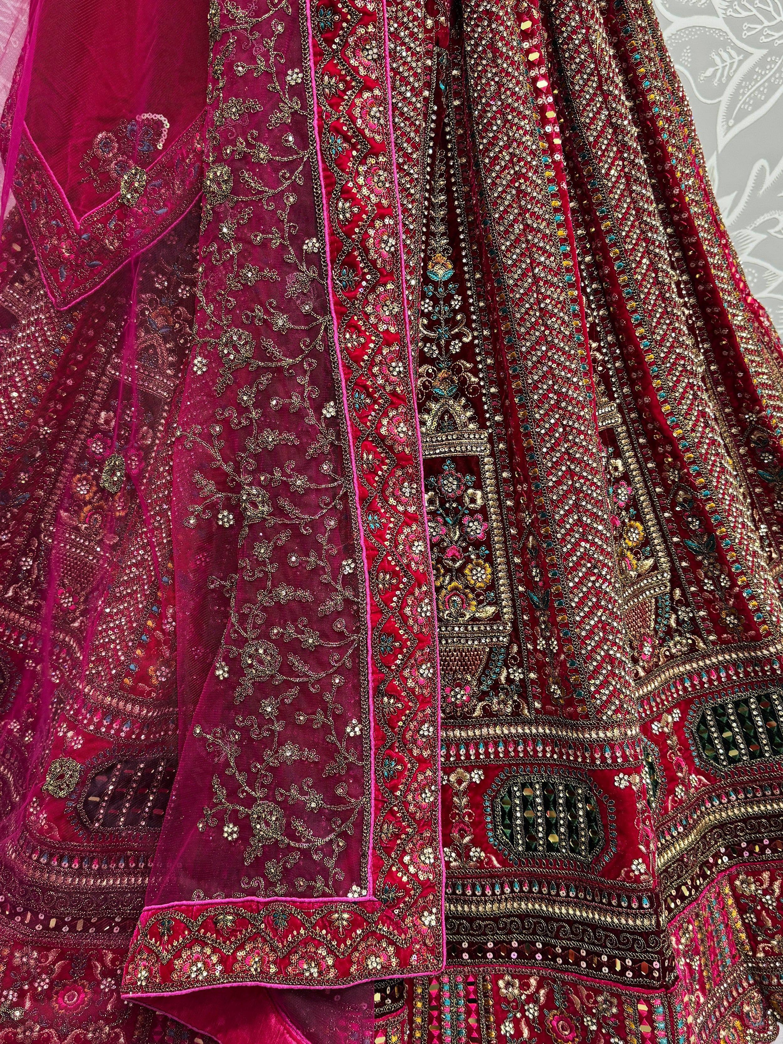 Luxury maroon lehenga choli with heavy gold embroidery and mirror work, perfect for Indian weddings and festive occasions.