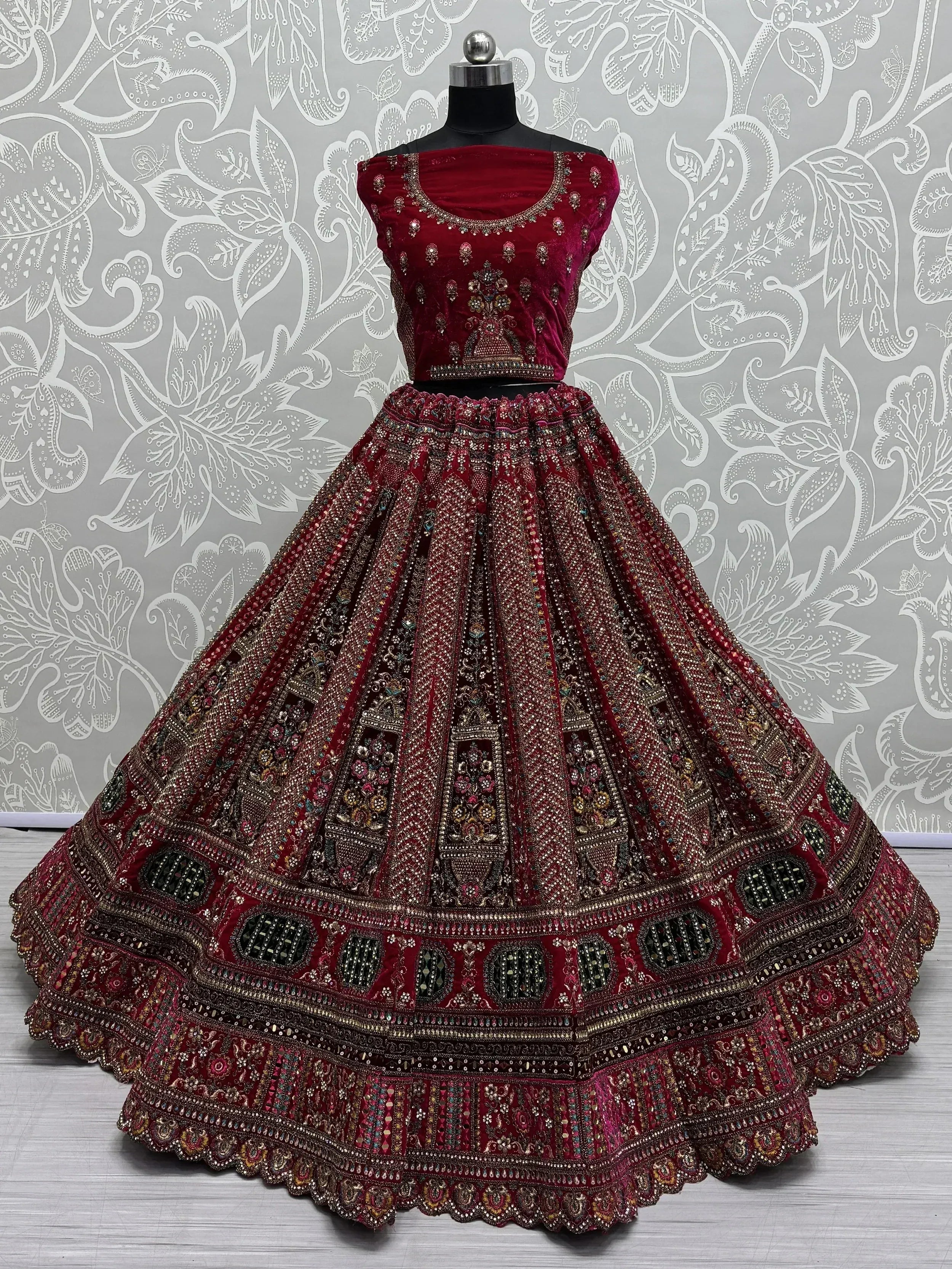 Maroon velvet designer lehenga choli with heavy embroidery and mirror work, perfect for Indian weddings and festive occasions.