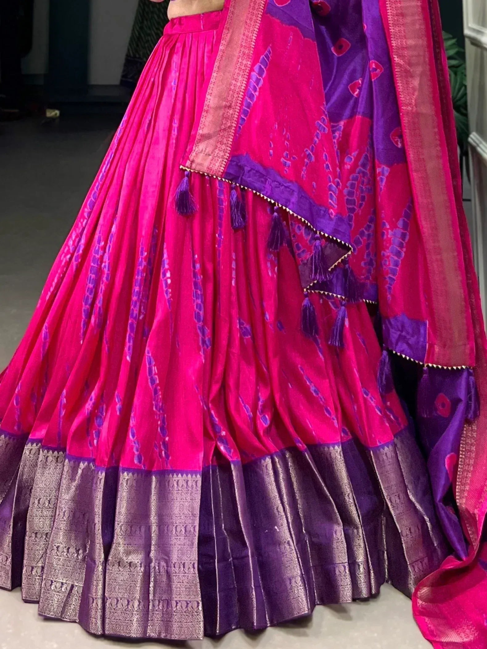 Vibrant pink and purple lehenga choli with pleated skirt, ikat print, and tassel detailing for Indian ethnic wear