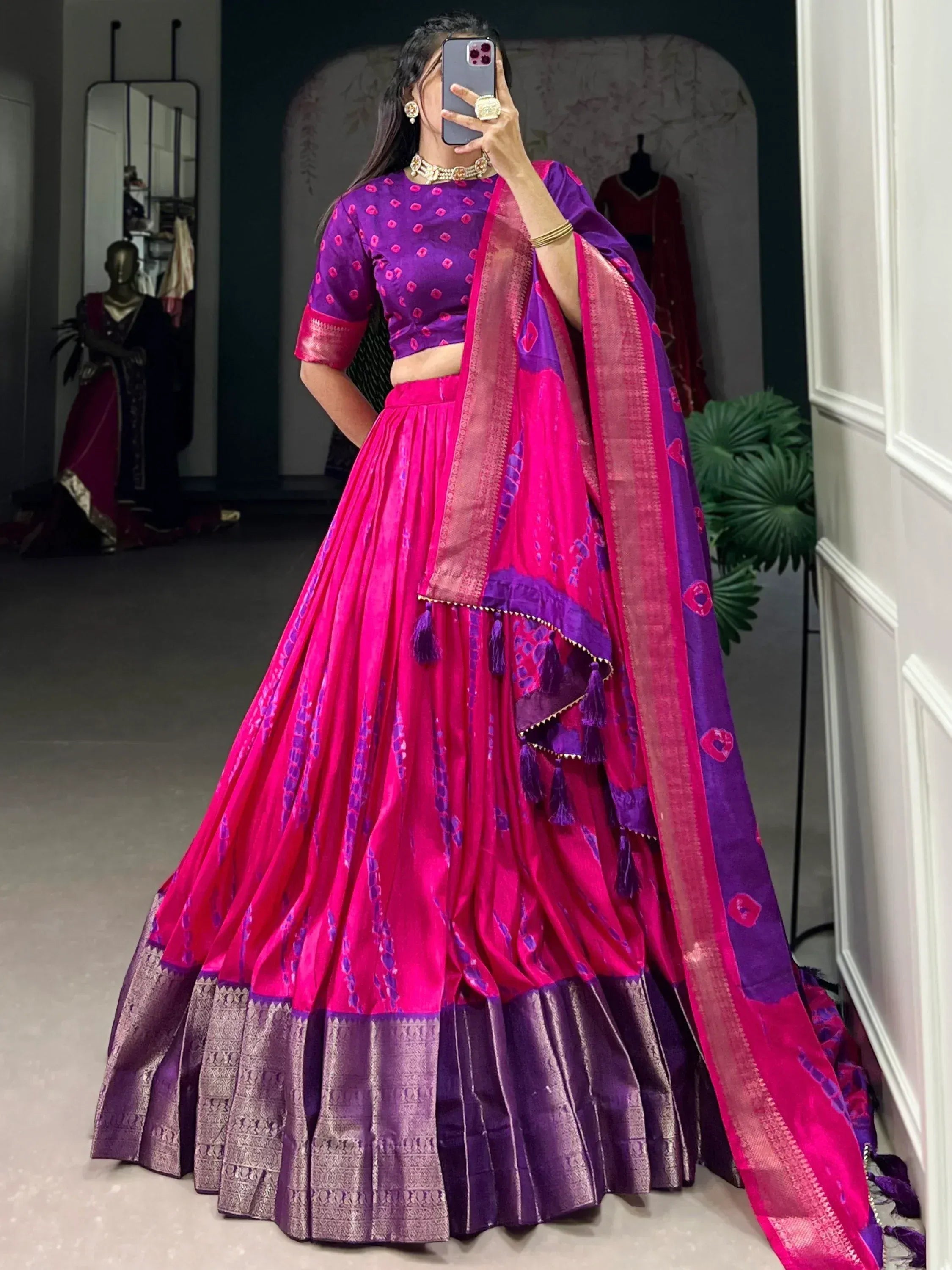 Vibrant pink and purple designer lehenga choli with intricate patterns and tassels, perfect for Indian ethnic wear.