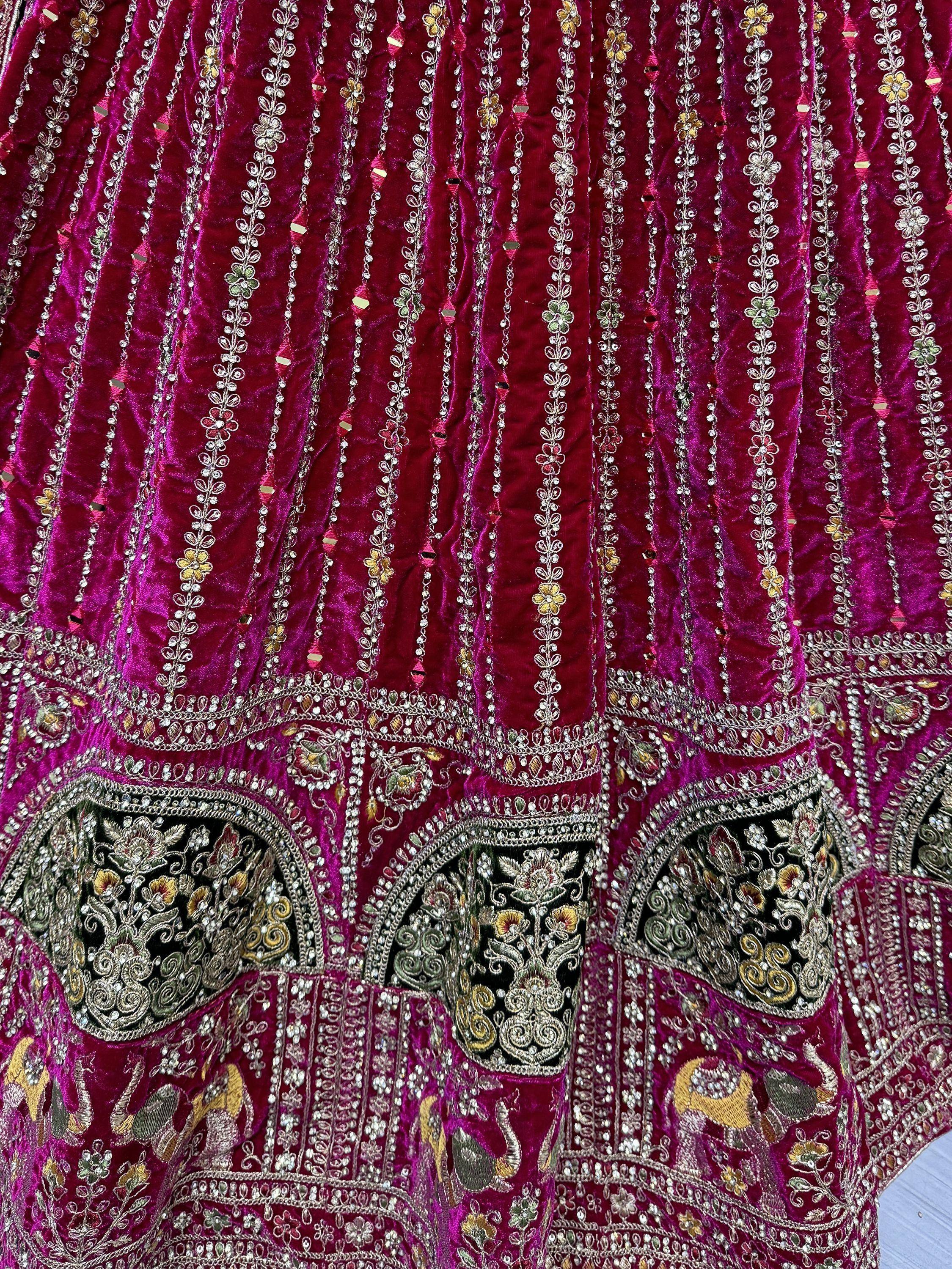 Rich maroon velvet lehenga with intricate floral embroidery, mirror work, and gold detailing for Indian ethnic wear.
