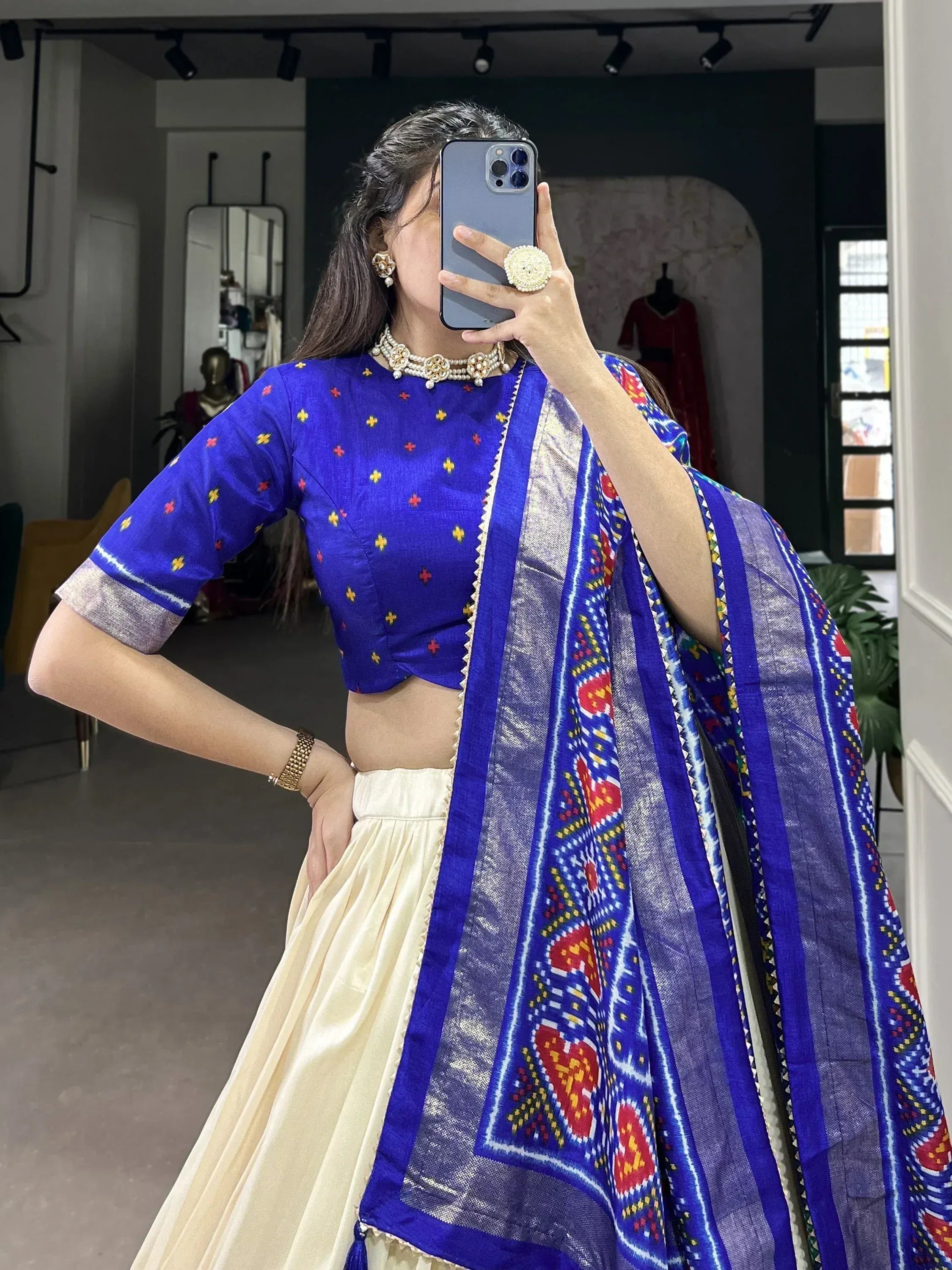 Woman in blue embroidered crop top with cream lehenga and colorful dupatta, Indian ethnic wear