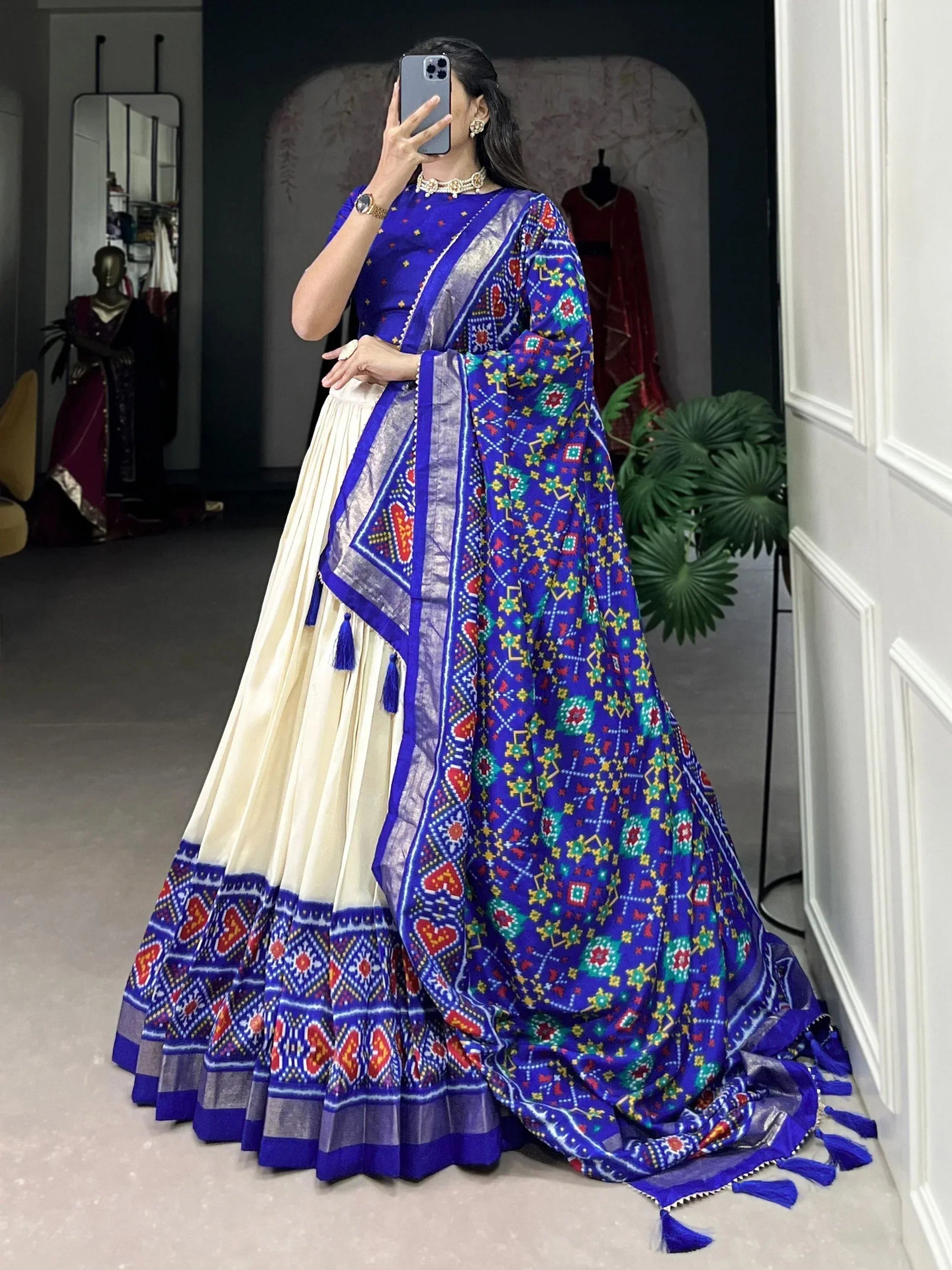 Blue and cream ethnic lehenga choli with colorful geometric print and tassels, perfect for Indian occasions.