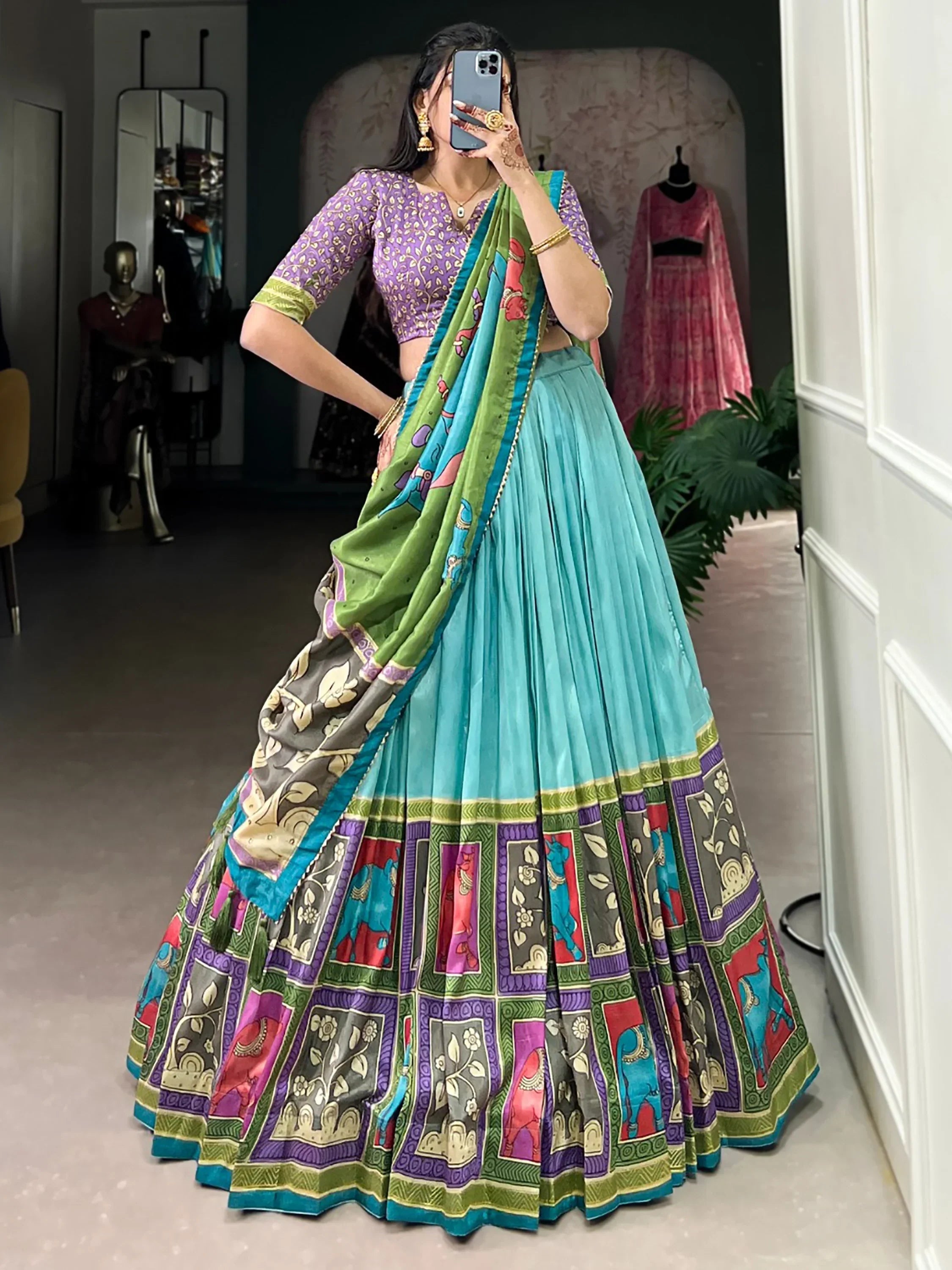 Woman in vibrant turquoise lehenga choli with purple blouse and printed dupatta, ethnic Indian wear