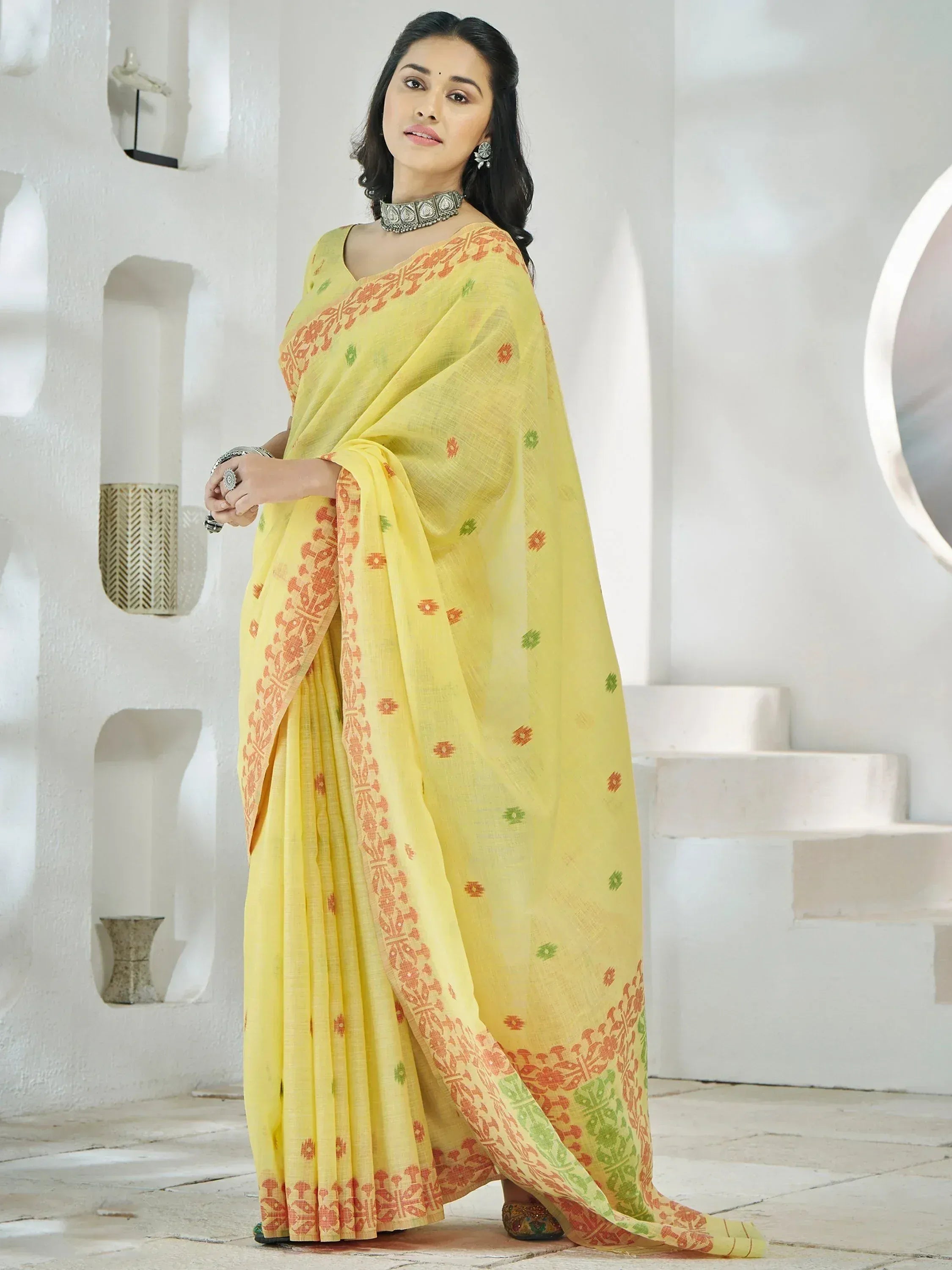 Yellow printed saree with orange and green motifs, styled with ethnic jewelry for Indian ethnic wear