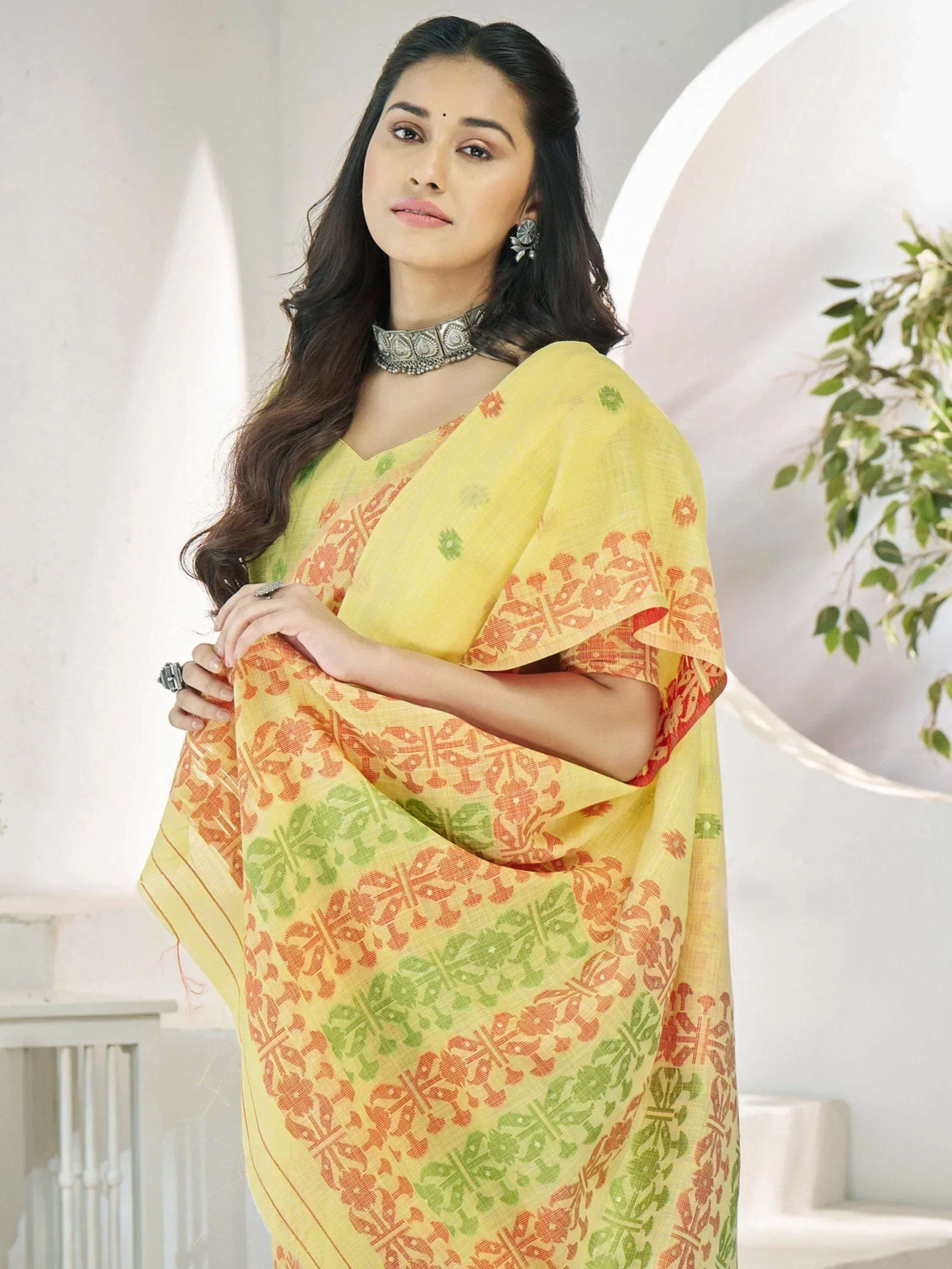 Yellow printed saree with orange and green floral motifs, styled with ethnic jewelry for traditional Indian wear