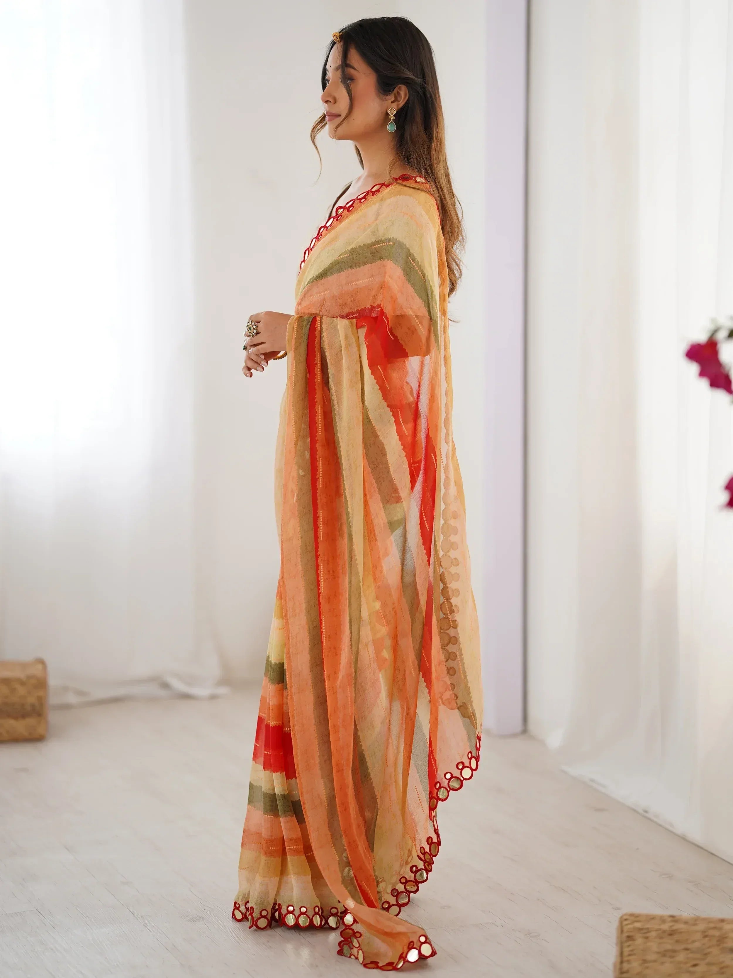Woman in vibrant orange and red ethnic saree with mirror work, perfect for Indian occasions