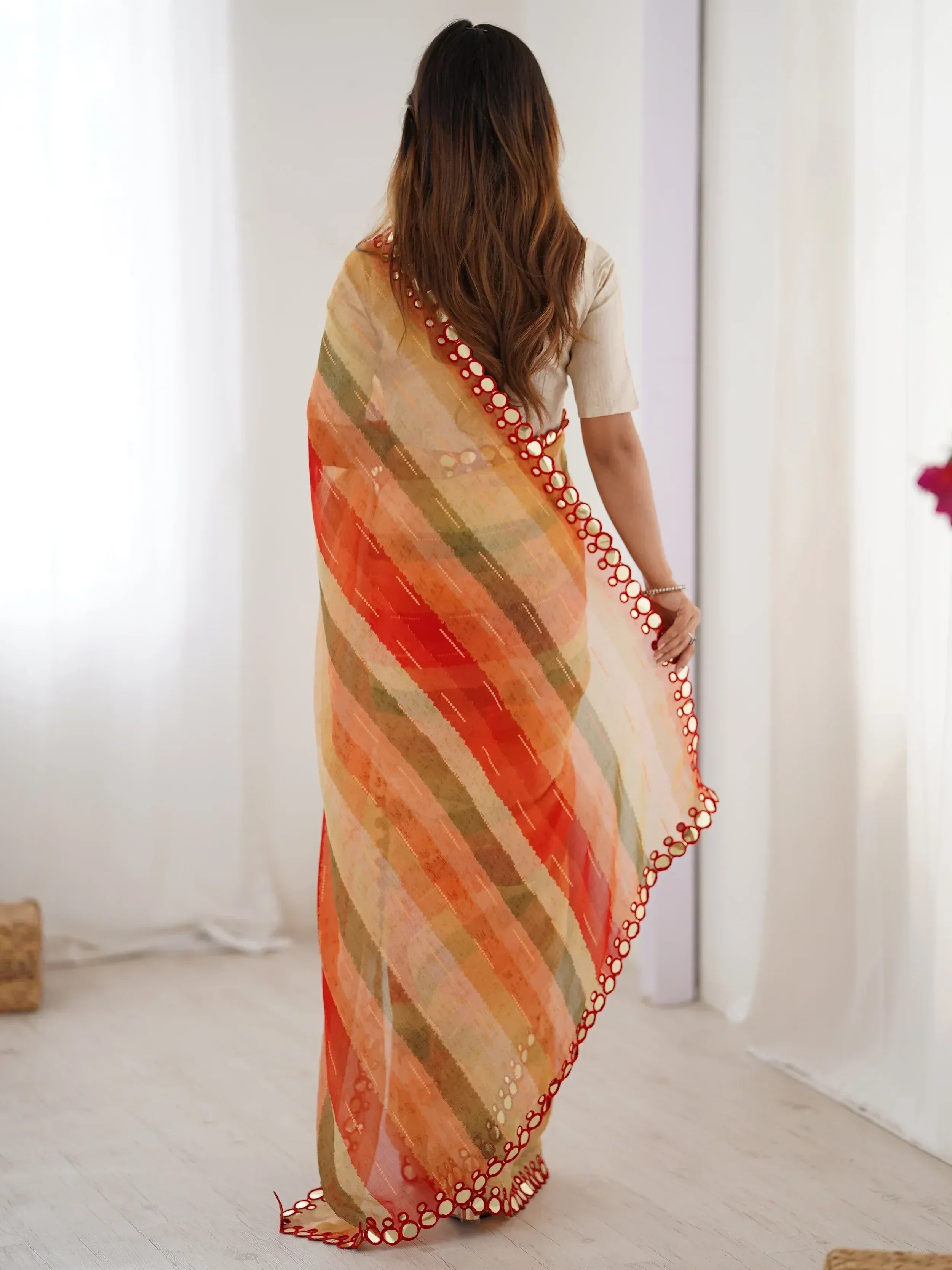 Woman in vibrant striped saree with mirror work, showcasing ethnic Indian wear