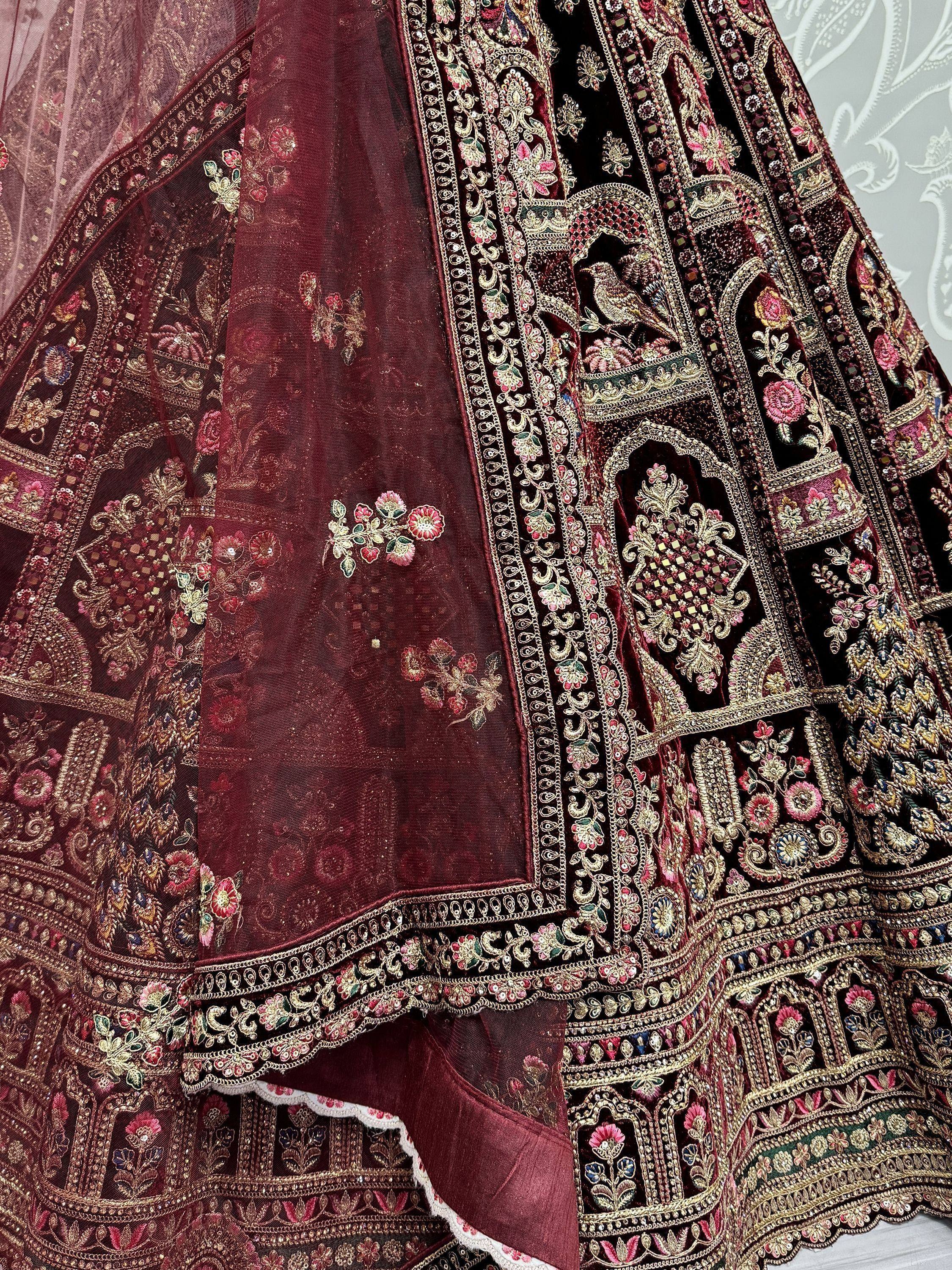 Luxury maroon lehenga choli with intricate gold embroidery and floral motifs, perfect for Indian weddings.