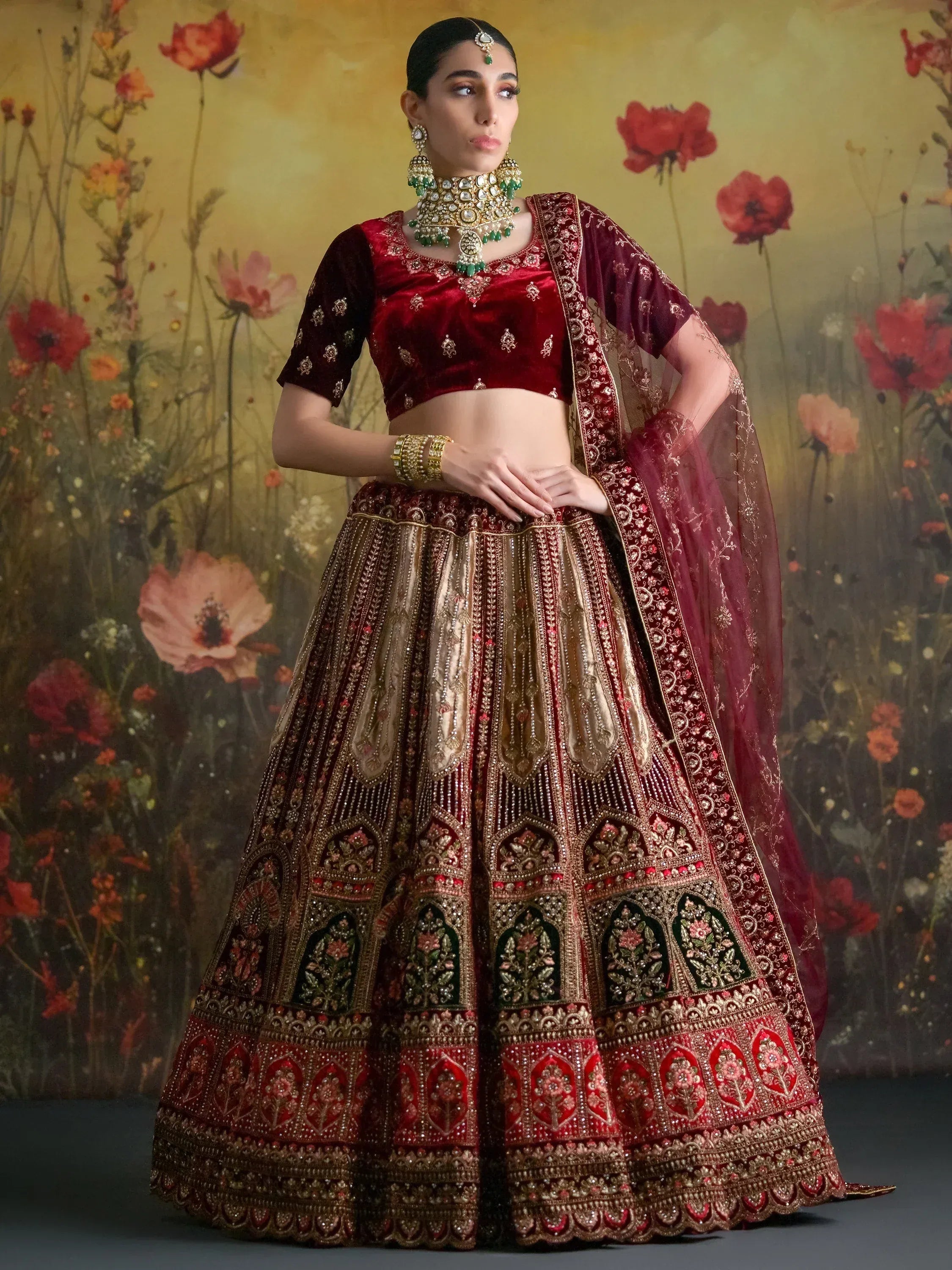 Luxury maroon velvet lehenga choli with heavy gold embroidery, perfect for Indian weddings and festive occasions.