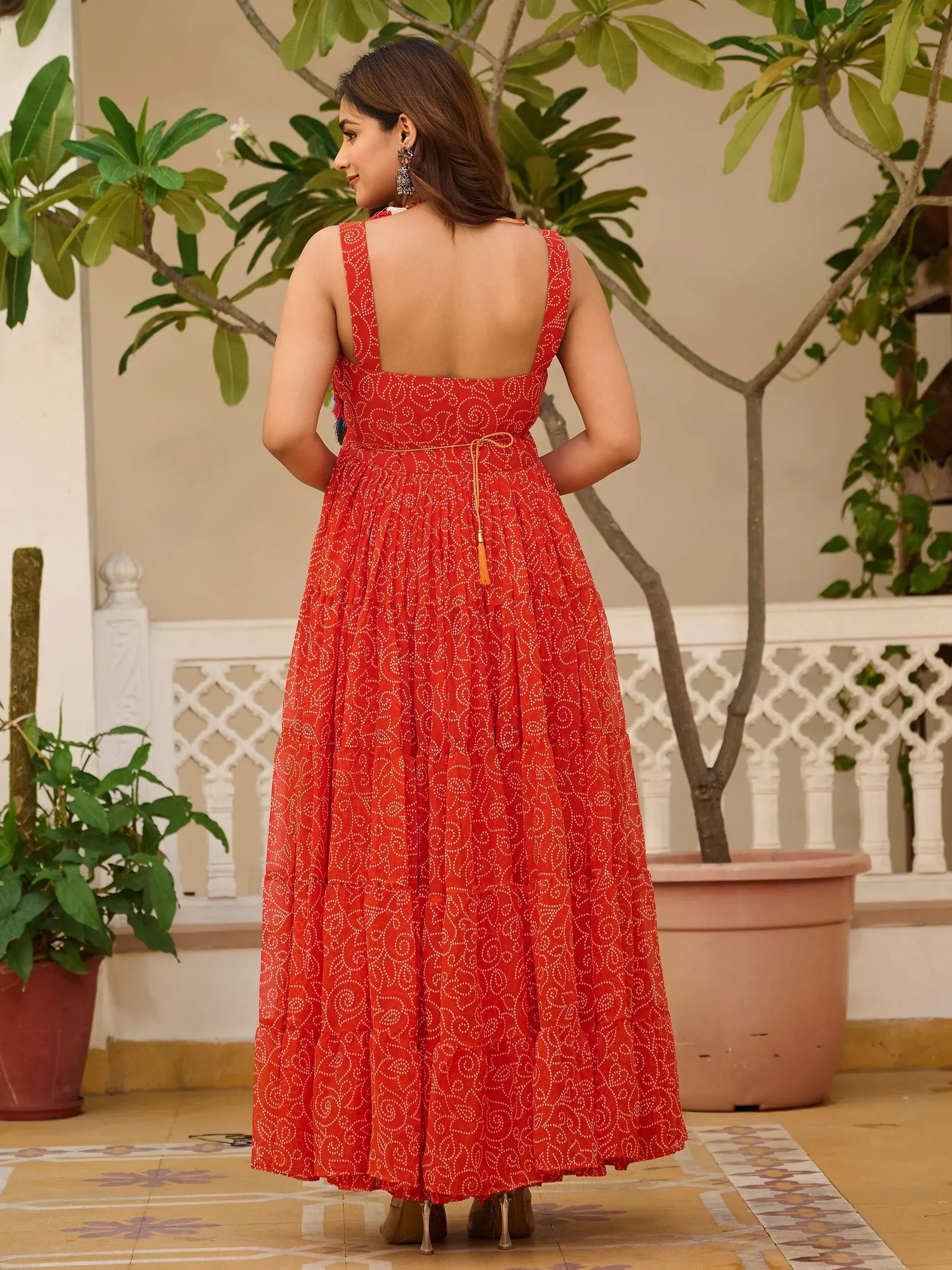 Red printed ethnic gown with backless design and tassel tie, perfect for Indian festive occasions