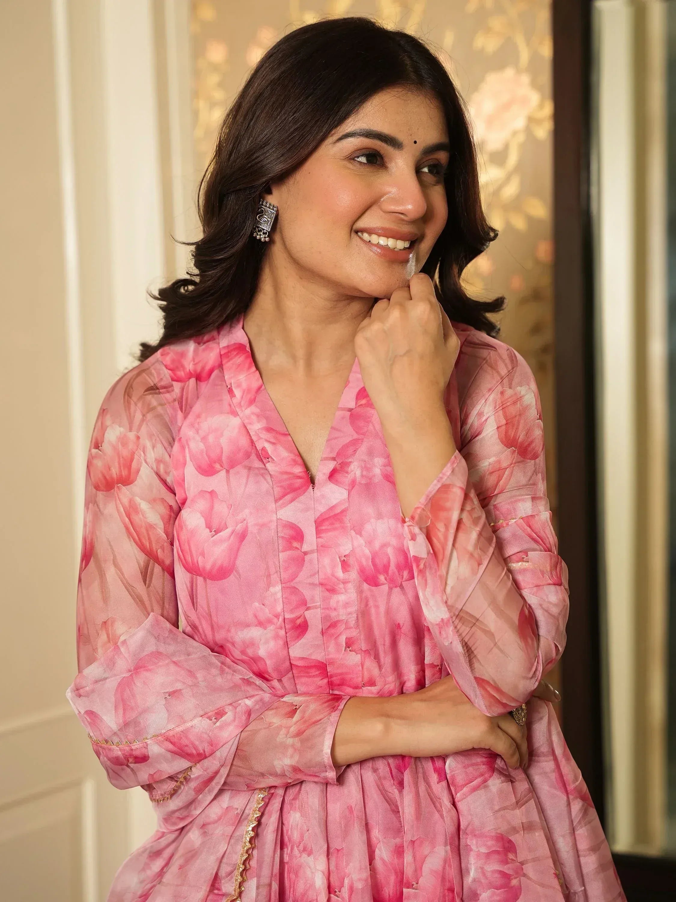 Pink floral printed ethnic gown with V-neck and flared sleeves, perfect for festive occasions.