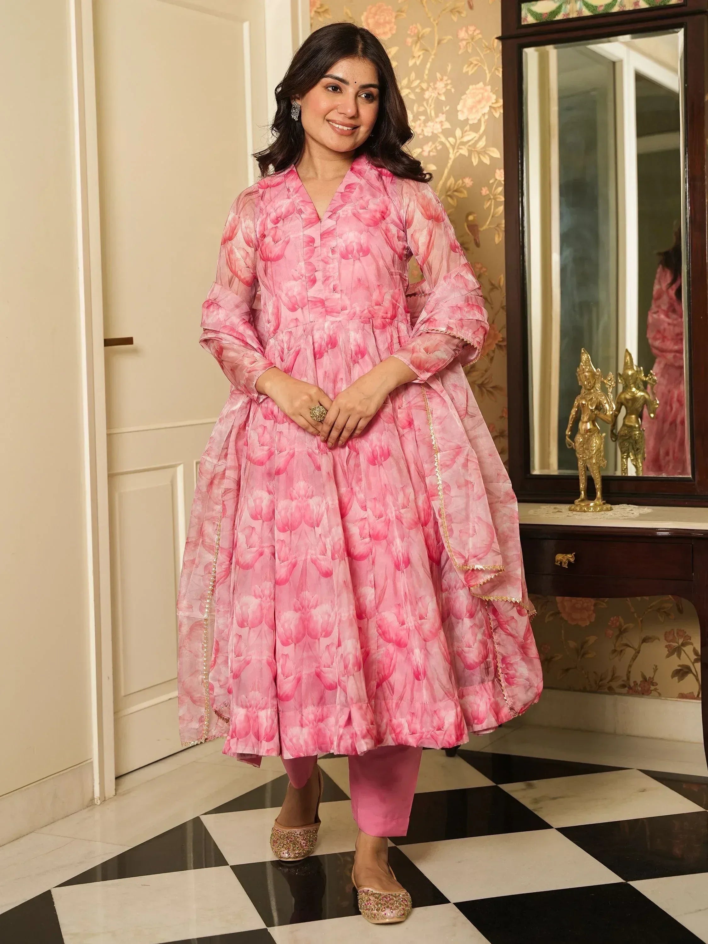 Pink floral printed anarkali suit with gold trim, paired with matching pants and embellished flats, perfect for ethnic occasions.