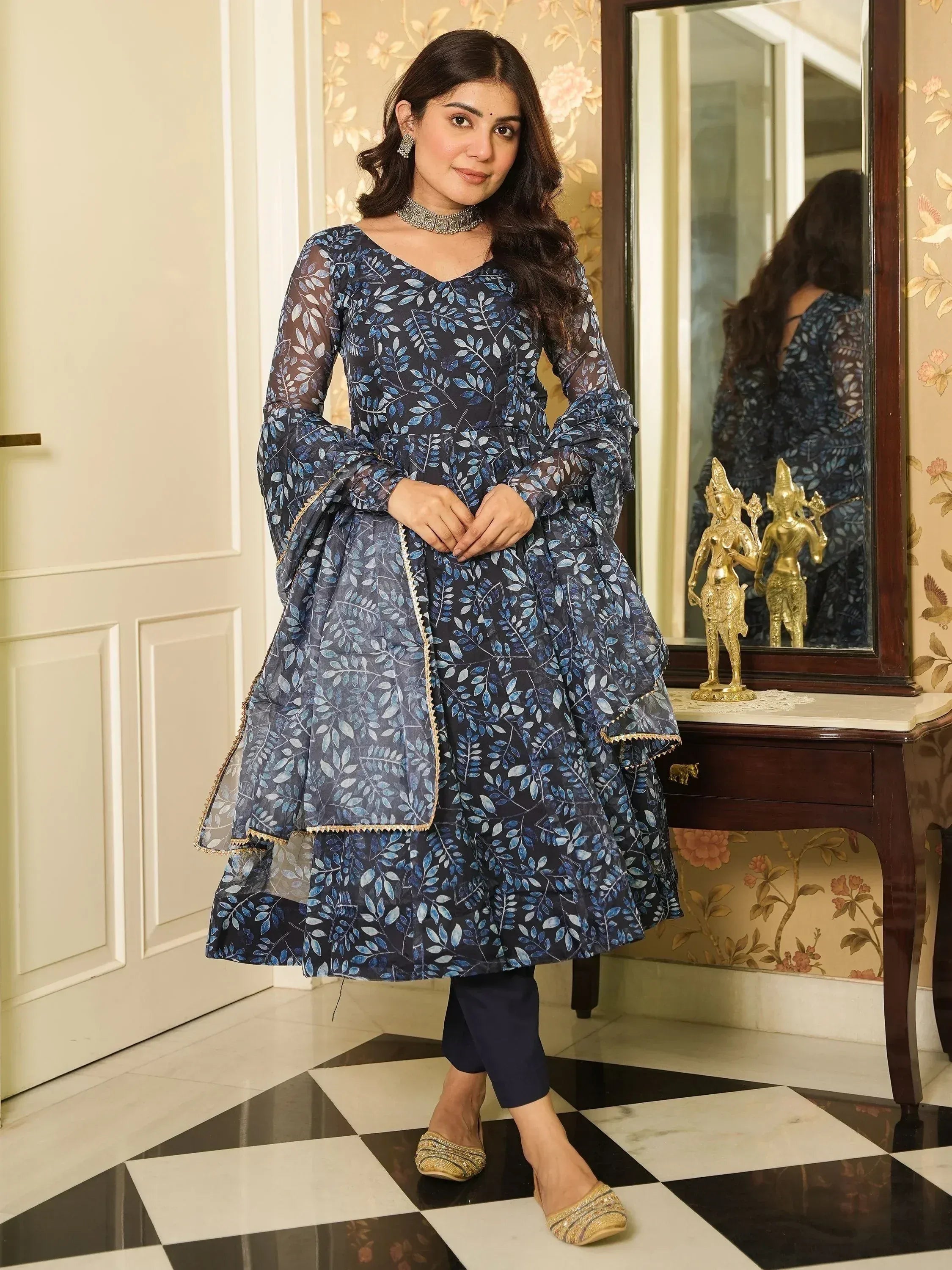 Elegant blue leaf-print ethnic gown with sheer sleeves, paired with navy pants and gold flats.