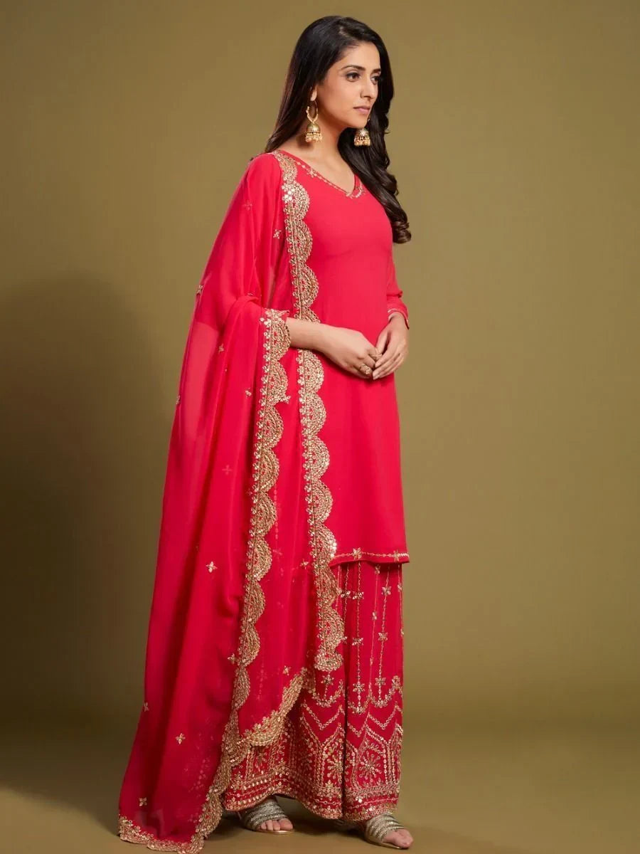Woman in red embroidered salwar kameez with gold dupatta and ethnic jewelry