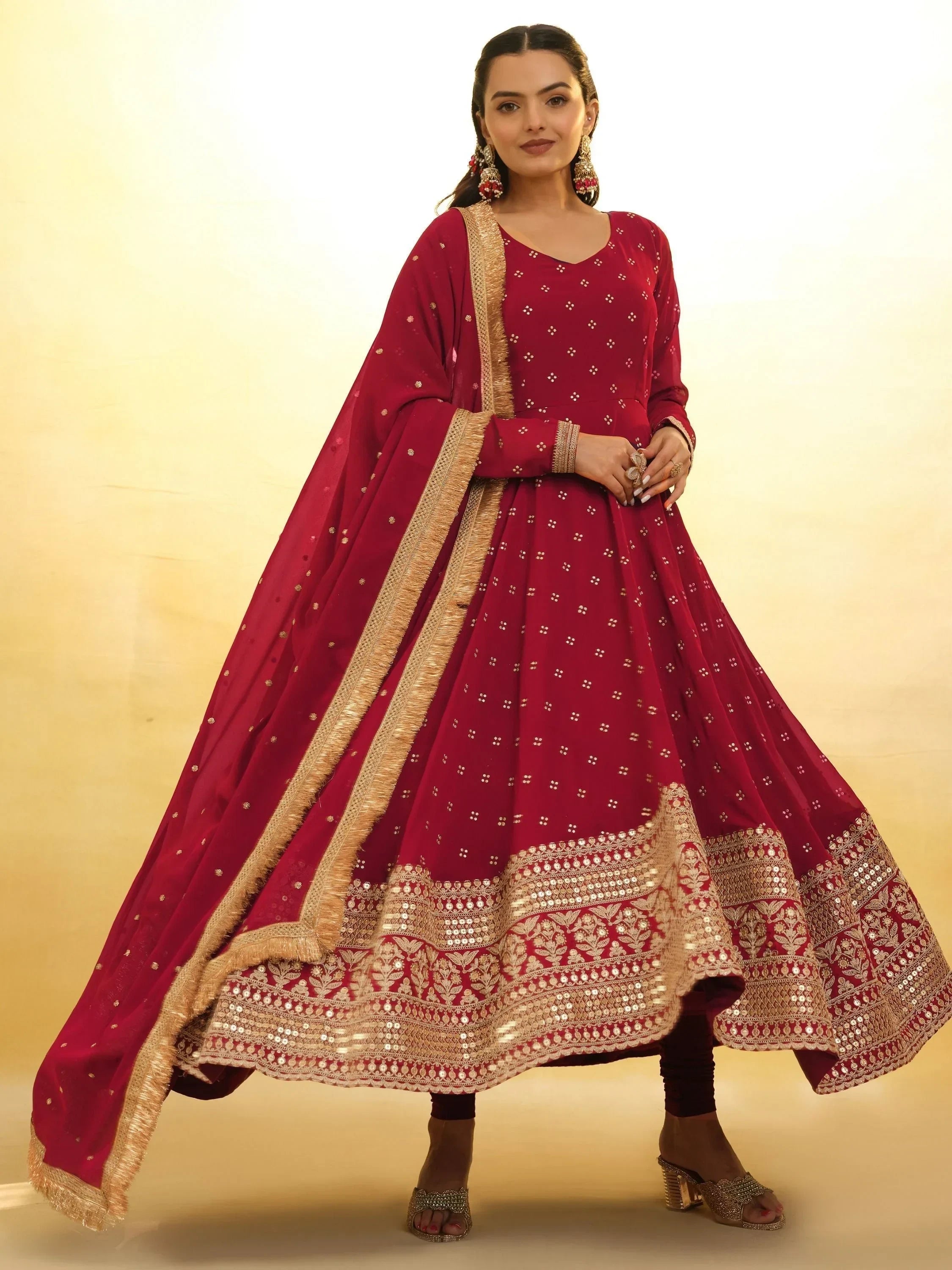 Woman wearing maroon embroidered Anarkali suit with gold dupatta, traditional Indian attire