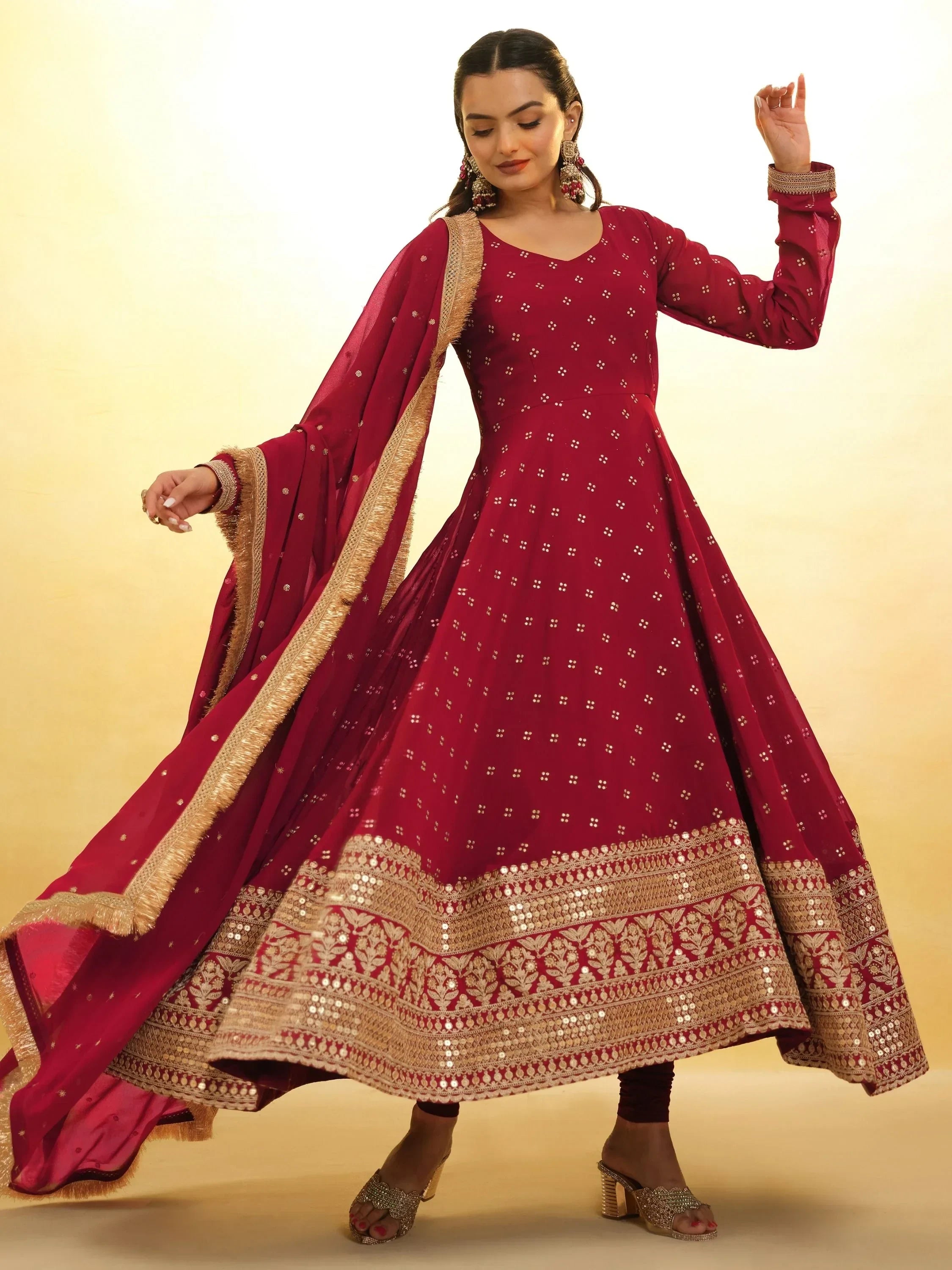 Woman in maroon Anarkali suit with golden embroidery and dupatta, traditional Indian attire