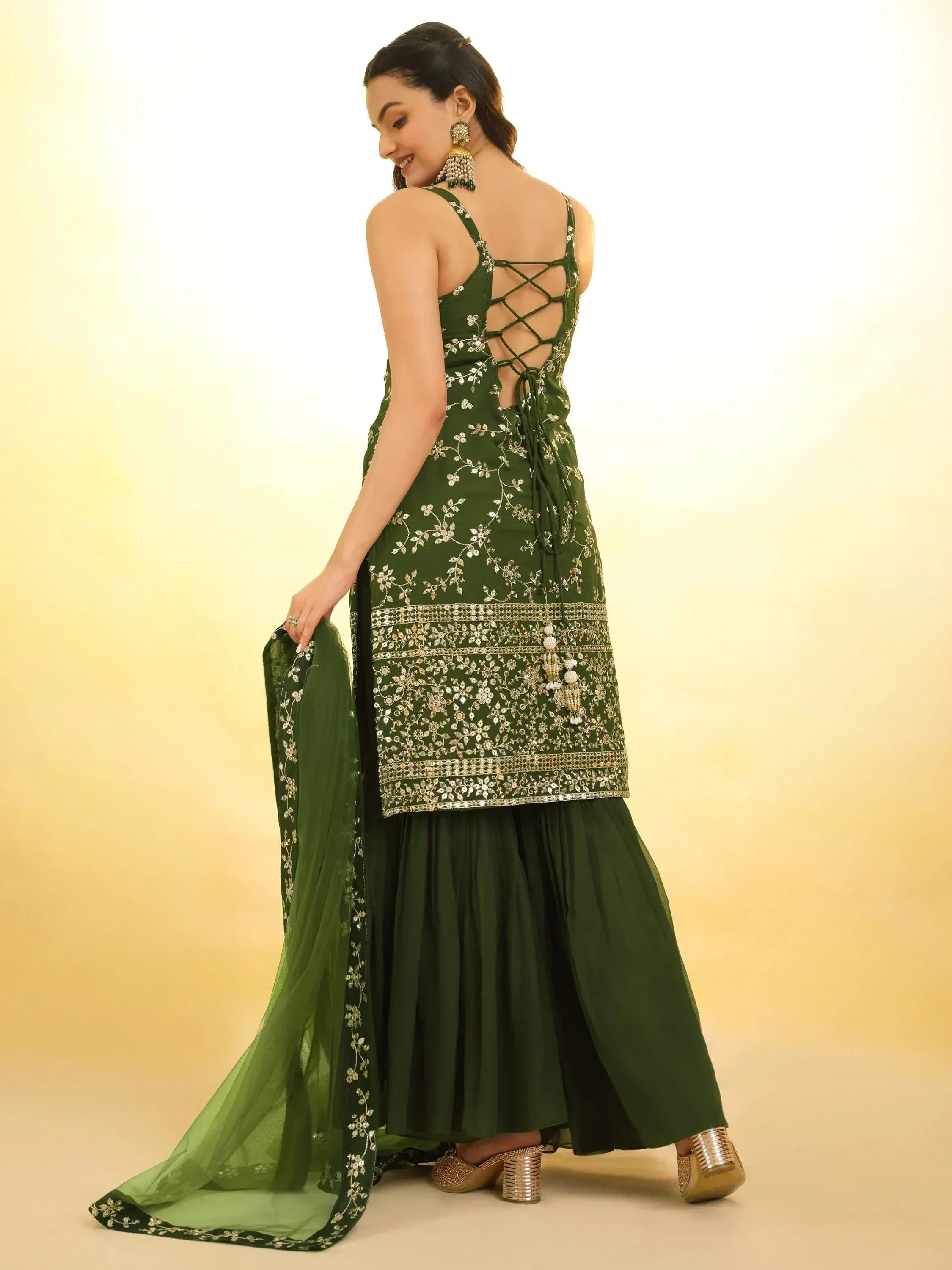 Emerald green embroidered ethnic gown with crisscross back, paired with matching dupatta and gold heels.