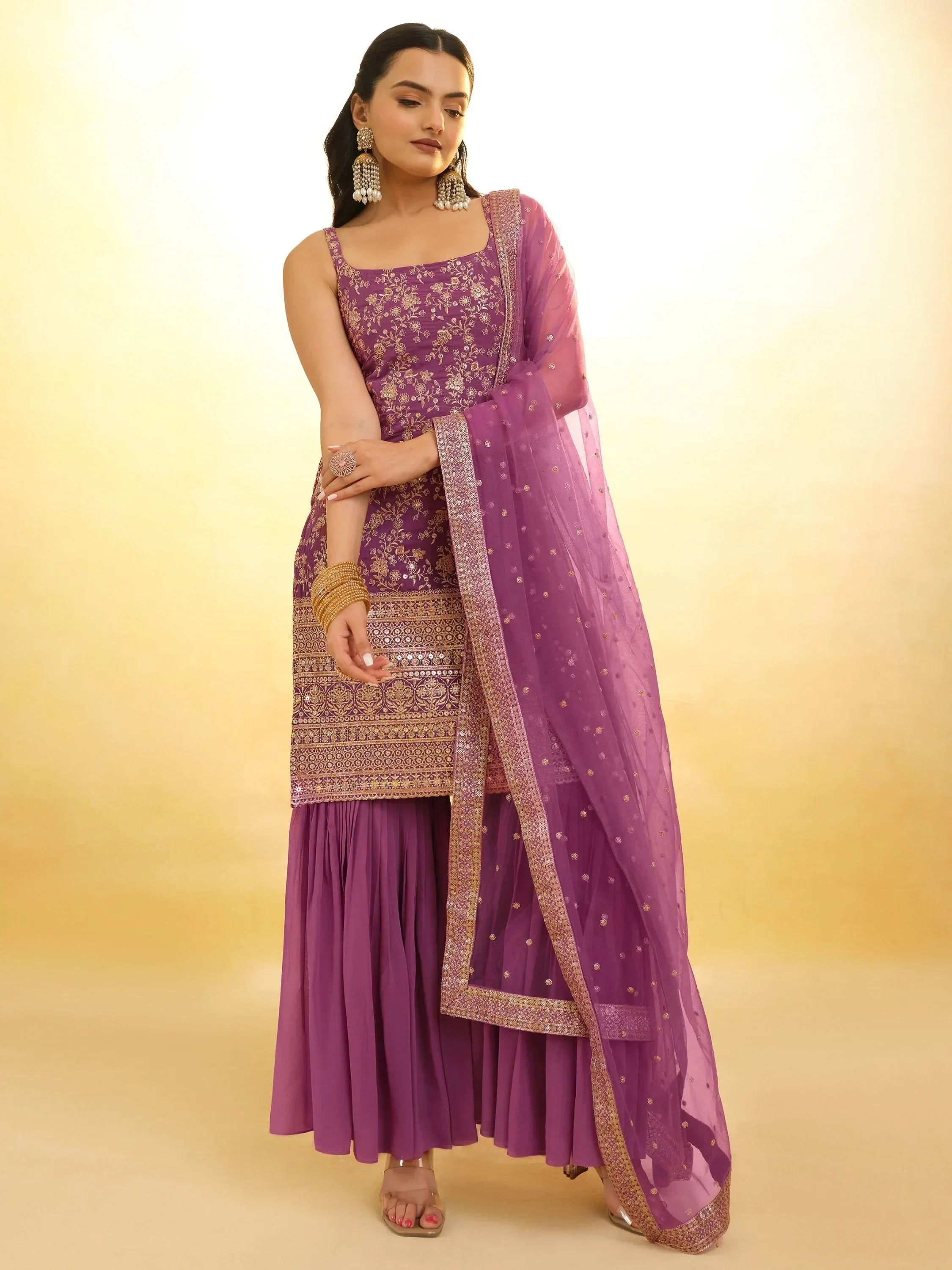 Woman wearing purple embroidered sharara suit with dupatta and traditional jewelry